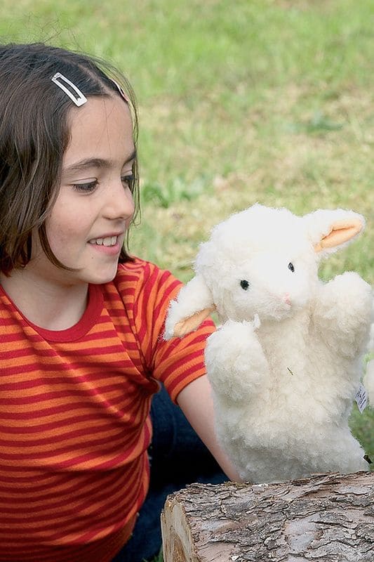 Handpuppe Schaf Mädchen mit gestreiftem Shirt hält weiße Handpuppe in Form eines Schafes