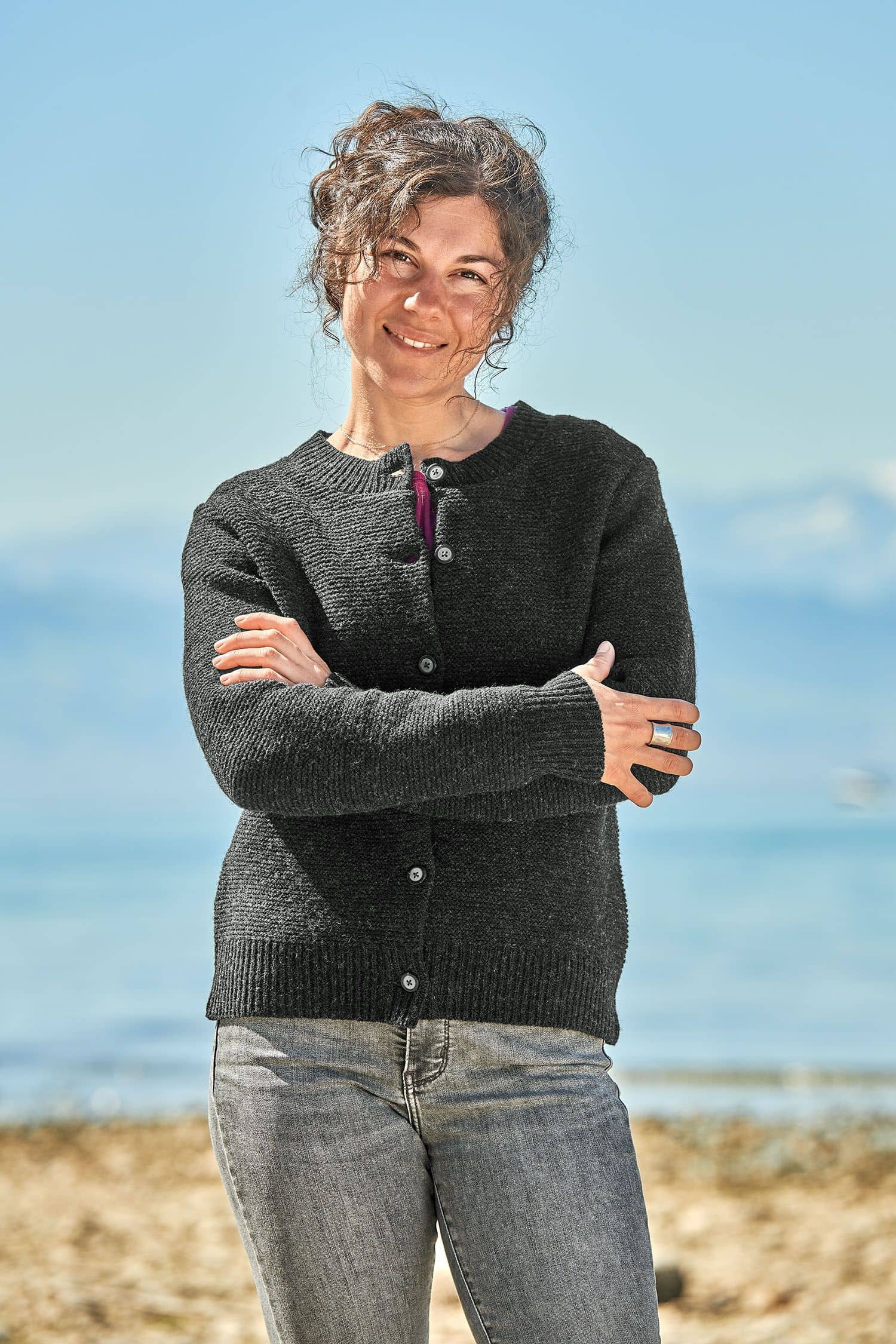 Frau trägt eine graue Jeans und eine dunkelgraue Strickjacke vom Finkhof aus bio Merinowolle (kbT)