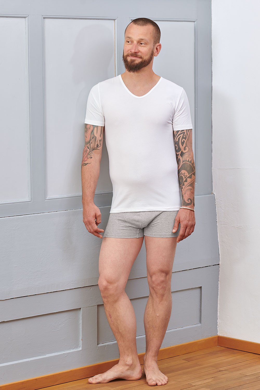Baumwoll-Herren-Kurzarmshirt aus Bio-Baumwolle Mann trägt graue Boxershorts und ein weißes Kurzarmshirt aus bio Baumwolle (kbA) und Elasthan mit V Ausschnitt