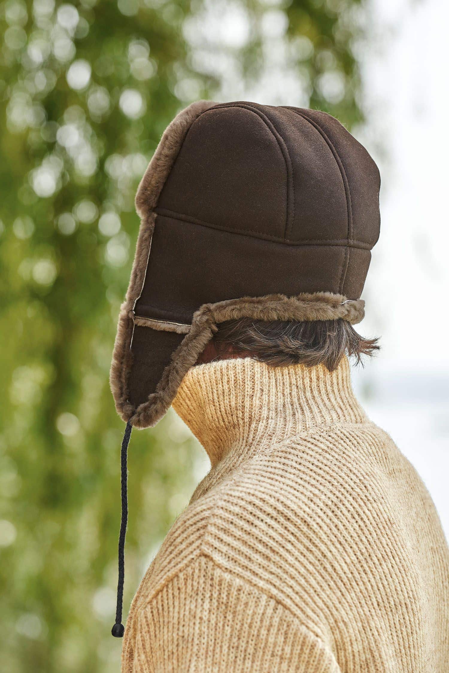 Rückansicht von Mann mit Finkhof Troyer trägt eine braune Fellmütze aus Schaffell vom Finkhof