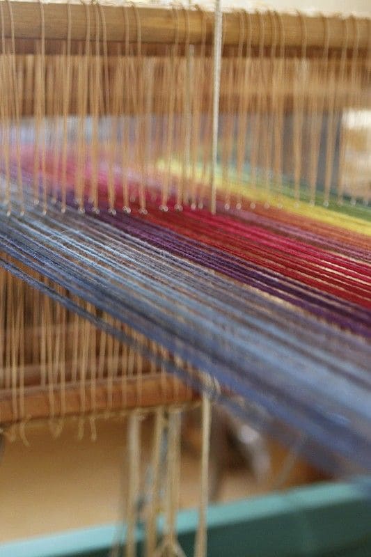 Nahaufnahme von Webstuhl mit Regenbogengarn auf dem Finkhof