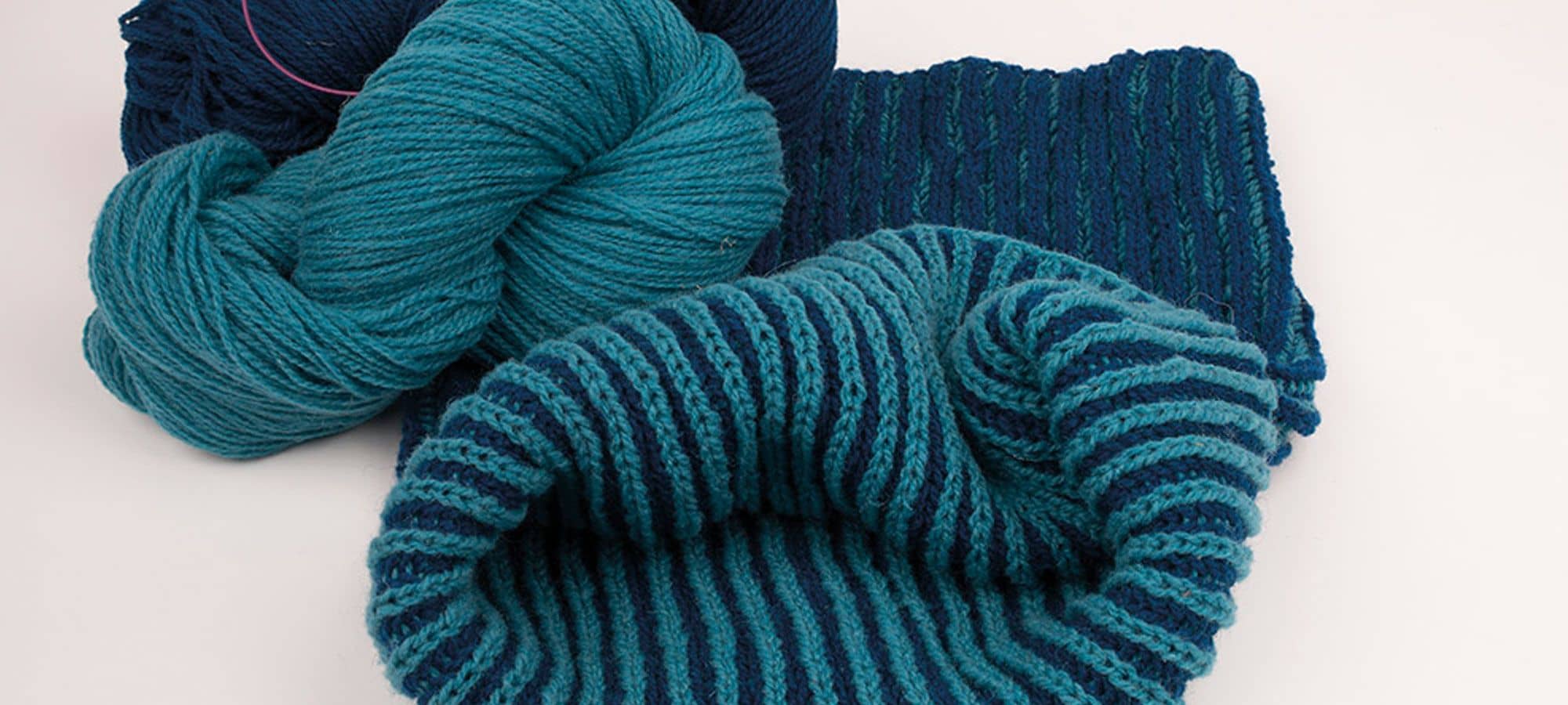 Strickanleitung Loop Merinowolle blauer Strickloopschal mit blauen Wollknäulen daneben