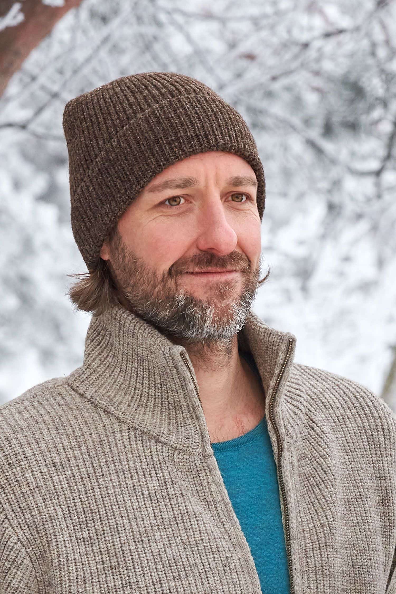 Mann trägt braunen Finkhof Troyer und eine dunkelbraune Finkhof Mütze aus bio Wolle (kbT)