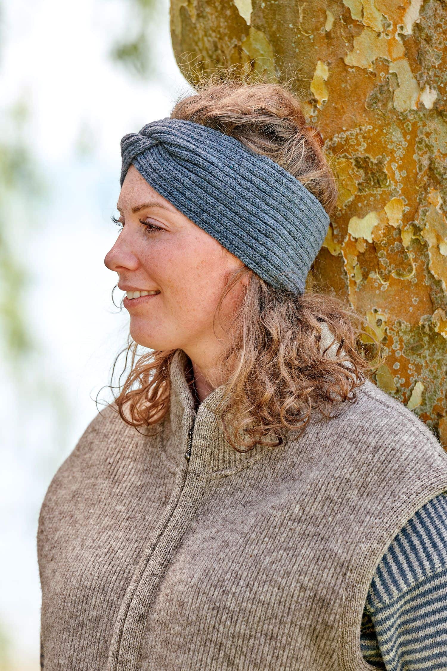 Frau trägt braune Weste und rauchblaues Stirnband mit Twist aus bio Wolle (kbT) vom Finkhof