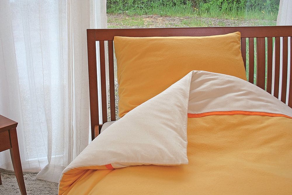 Frischer Wind und gute Laune mit hochwertiger Bettwäsche aus reiner Baumwolle gelb weiße Biberbettwäsche zum Wenden in braunem Holzbett