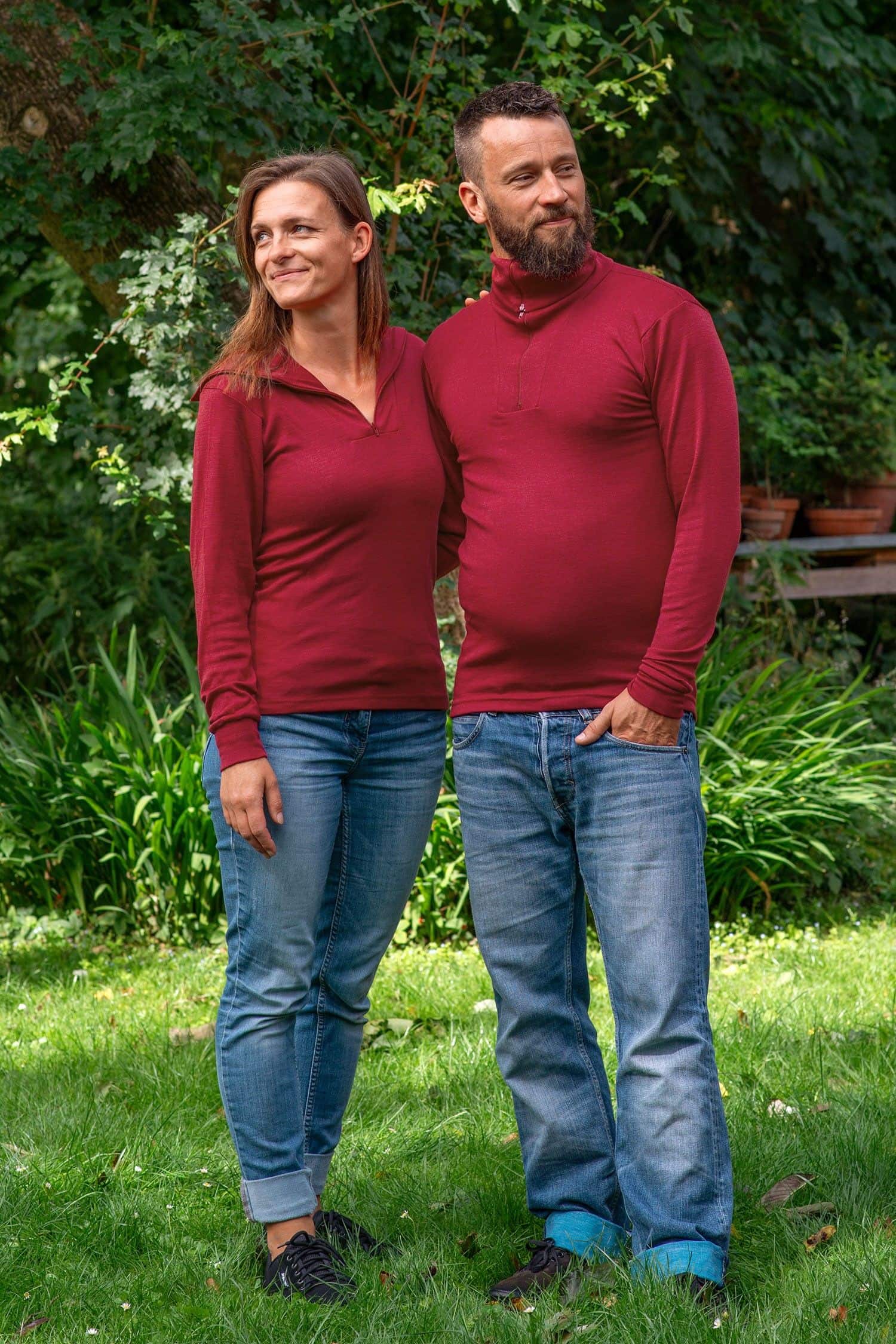 Mann und Frau stehen im Garten und tragen Jeans und roten Sportrolli aus bio Wolle (kbT) und Seide mit Reißverschluss