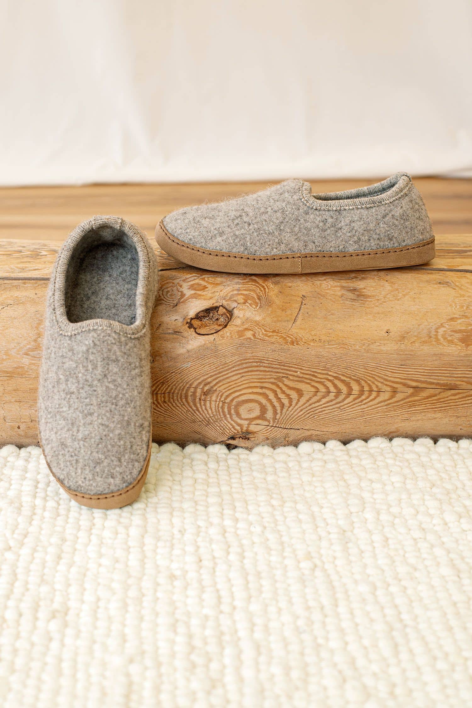 hellgraue Finkhof Hausschuhe aus bio Wolle (kbT) und pflanzlich gegerbtem Leder auf Holzstamm