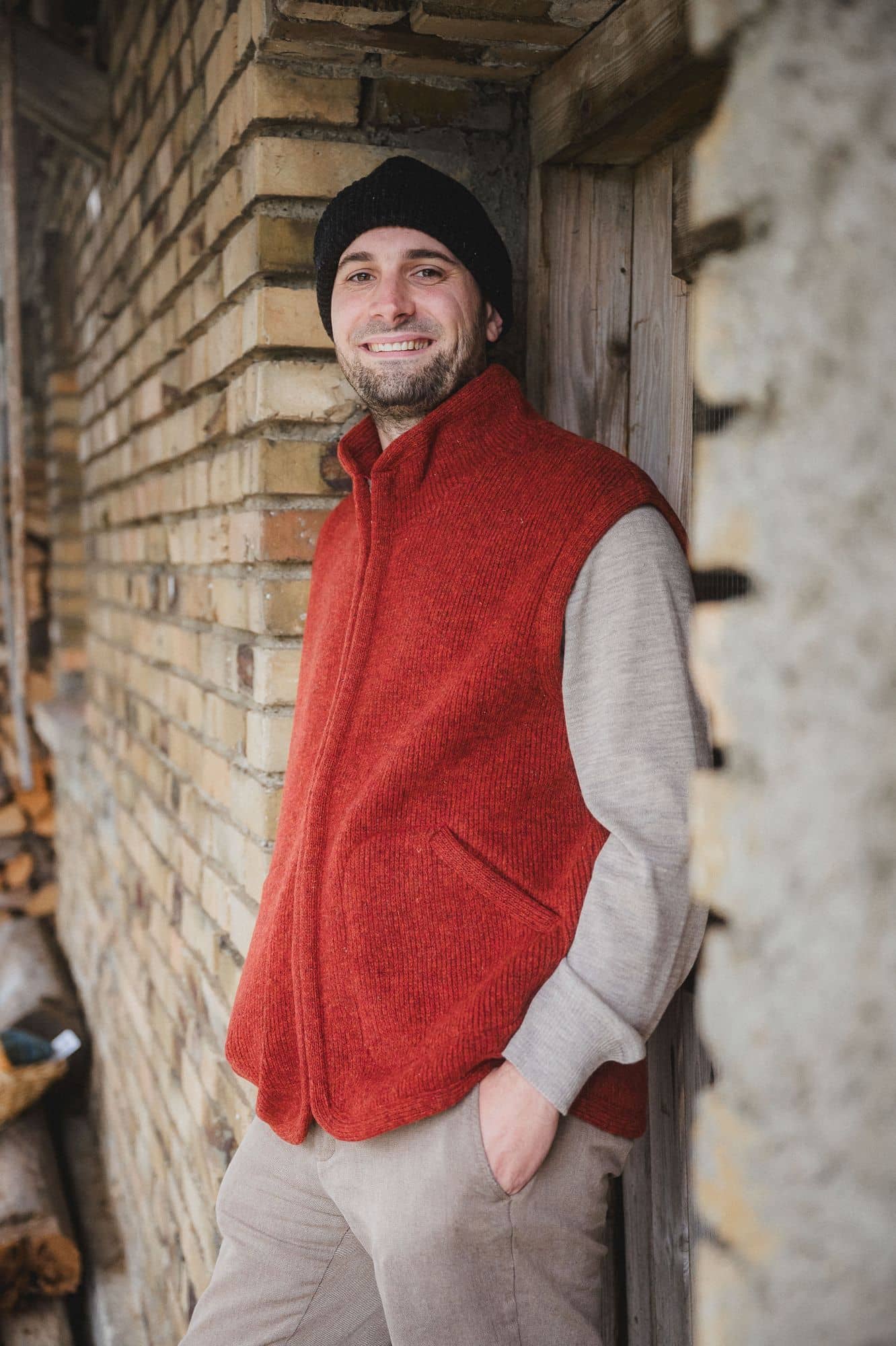 Mann trägt braunes Wollshirt, eine Mütze und eine rote Wollwalkweste aus bio Wolle (kbT) vom Finkhof