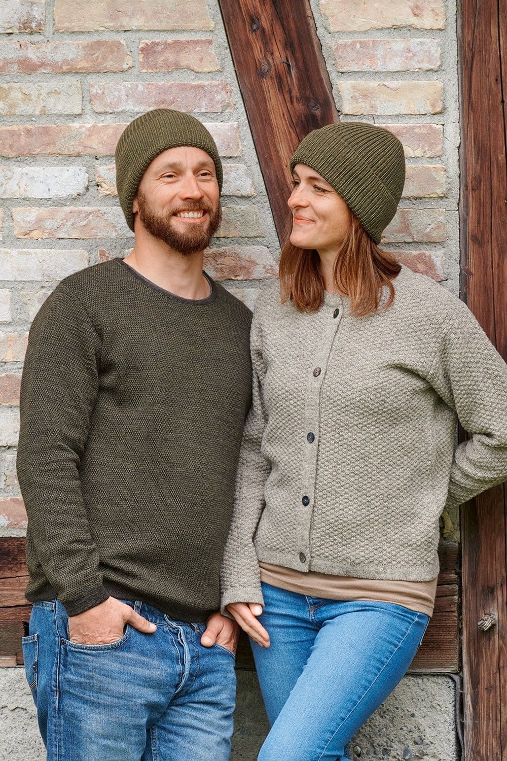 Mann und Frau mit Pulli und Weste tragen olivegrüne Wollmützen aus bio Wolle (kbT) vom Finkhof