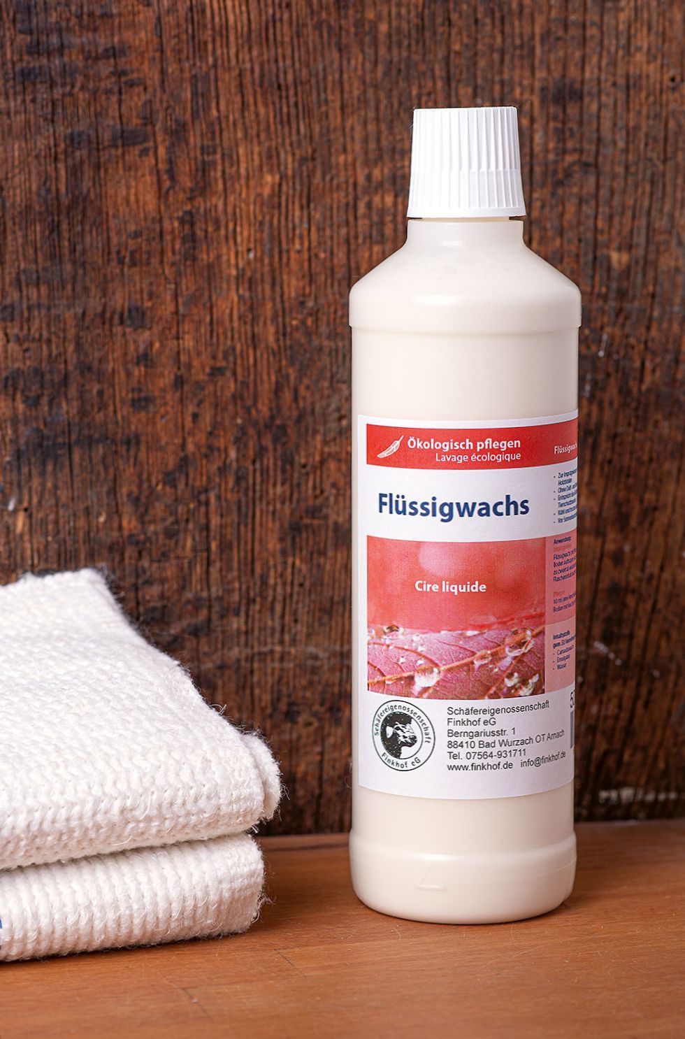 Finkhof Flüssigwachs in 500ml Flasche zum imprägnieren von Holz und Kork vor Holz mit weißen Handtüchern
