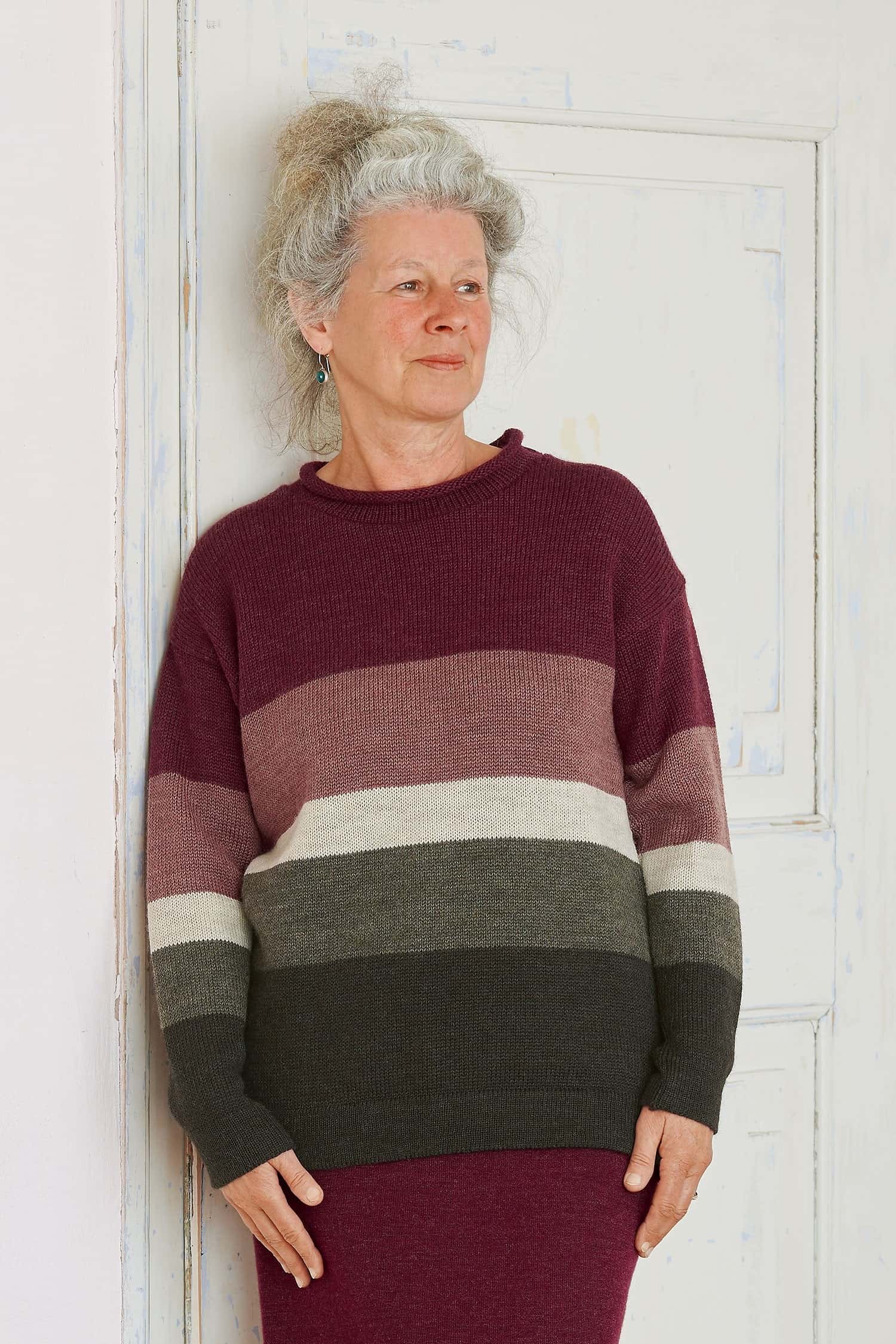 Frau trägt einen Pulli mit Blockstreifen in burgunderrot aus bio Wolle (kbT)