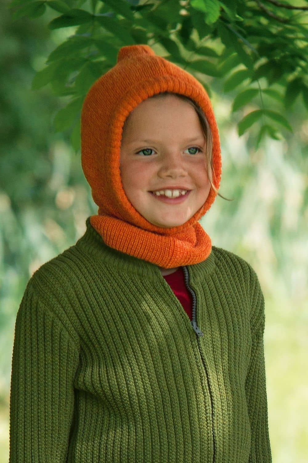 Kind mit grüner Weste trägt orange Schlupfmütze aus bio Wolle (kbT) und Seide vom Finkhof