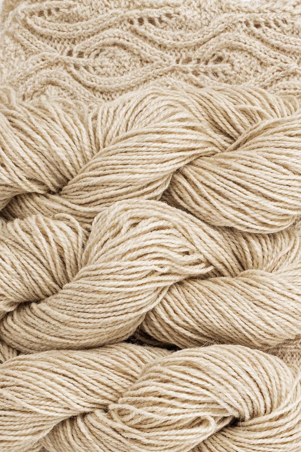 dicke ungefärbtes bio Wollgarn (kbT) vom Coburger Fuchsschaf vom Finkhof gedreht mit Strickstück im Hintergrund