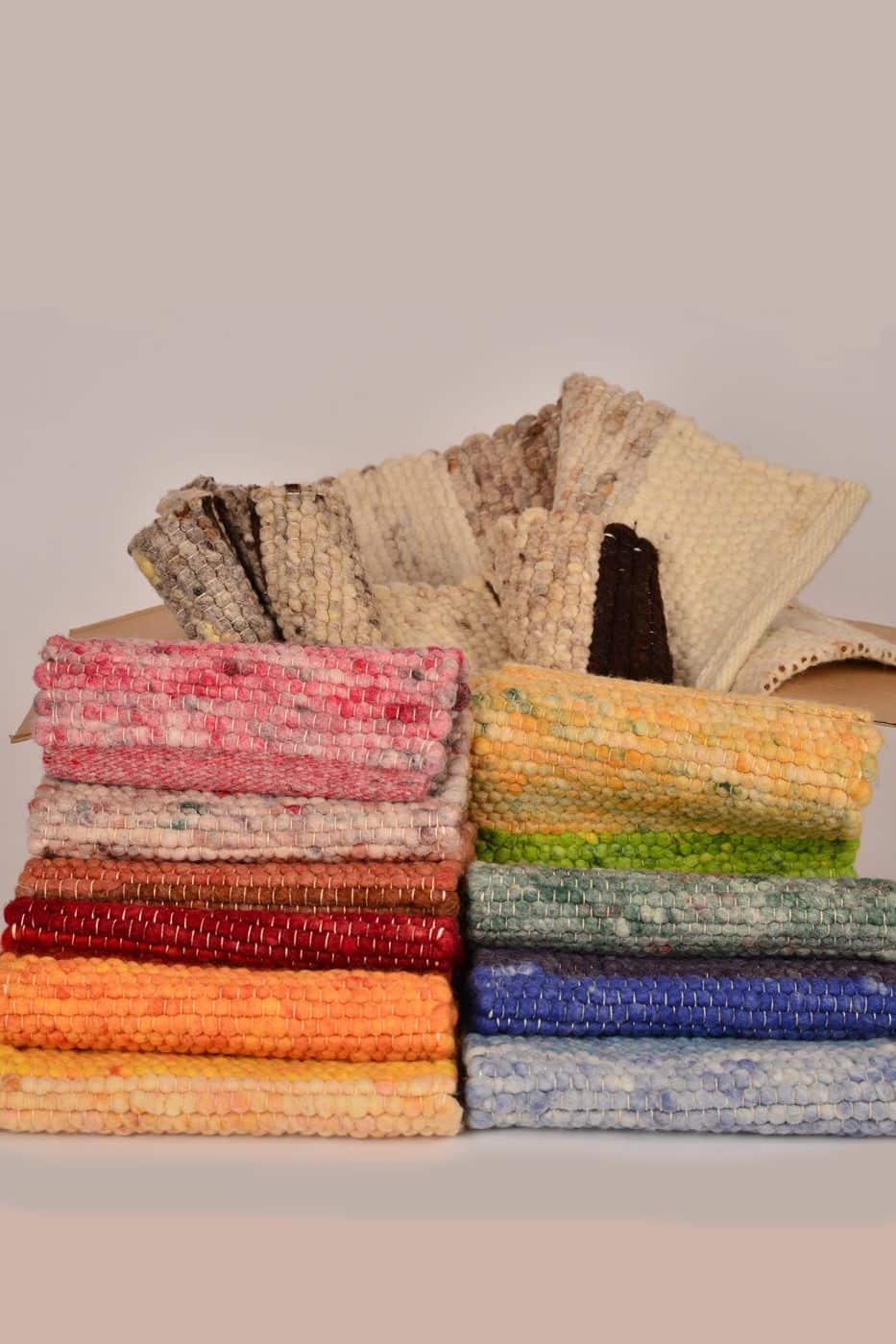 Musterpaket für Teppiche vom Finkhof in verschiedenen Farben gestapelt