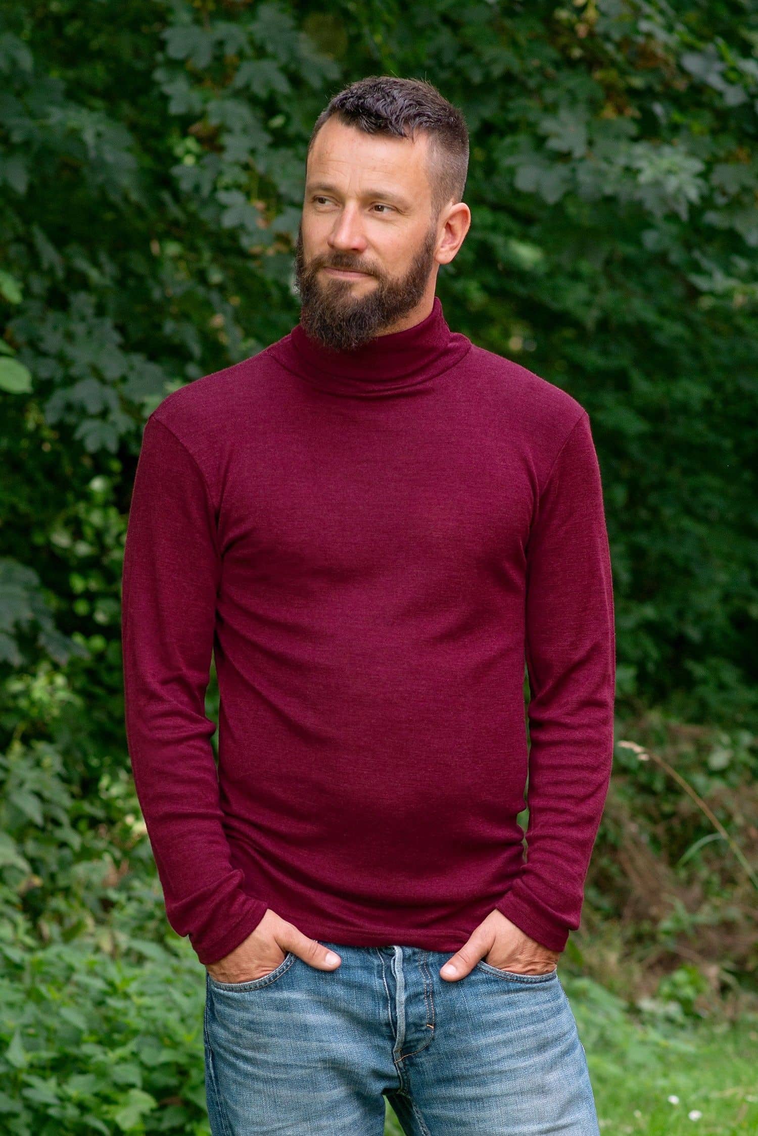 Mann im Garten trägt bordeauxroten Rollkragenpulli  aus bio Wolle (kbT) und Seide