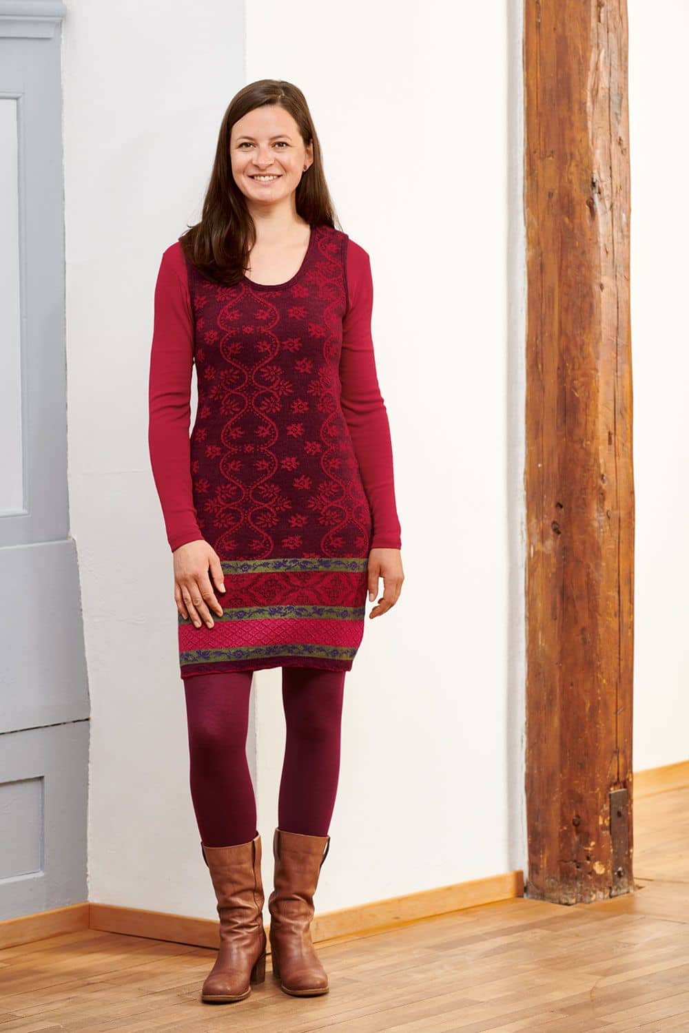 Trägerkleid Frau trägt burgerfarbenes gemustertes Trägerkleid aus bio Wolle (kbT) mit roter Strumpfhose und Shirt sowie Stiefeln