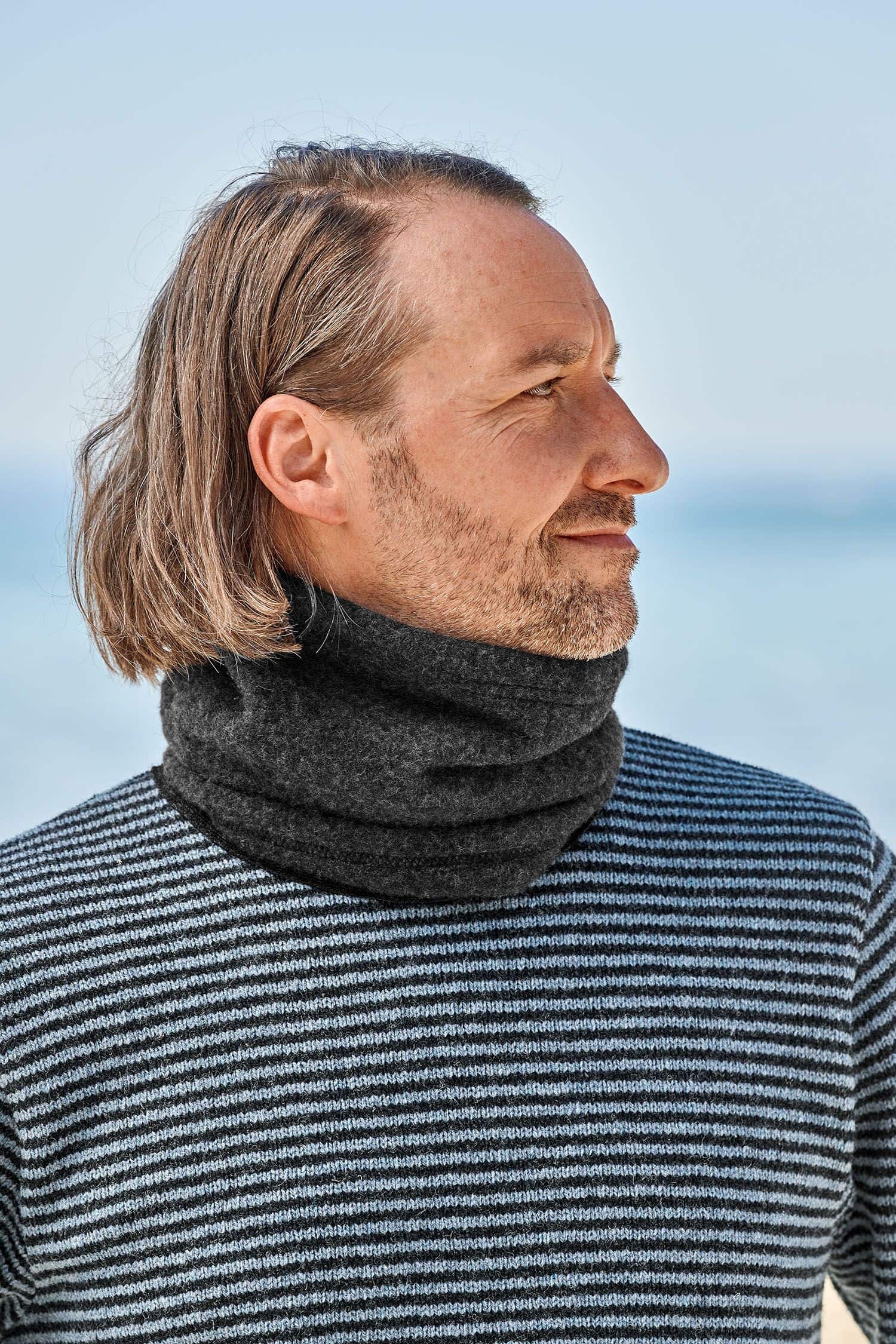 Mann mit Streifenpulli trägt anthrazitfarbenen Schlupfschal aus bio Merinowolle (kbT) vom Finkhof
