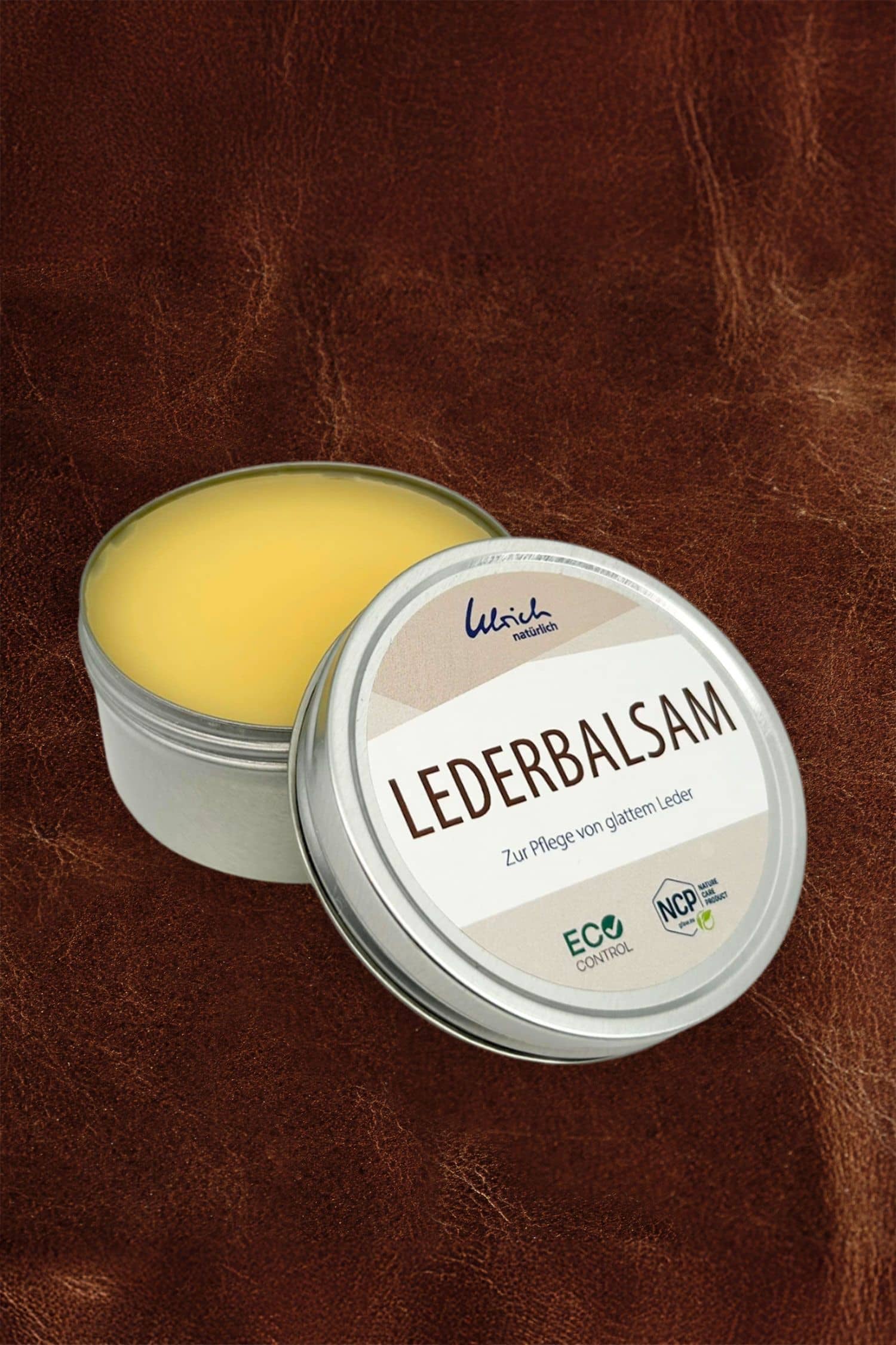 Lederbalsam 150 ml geöffneter silberfarbener 150 ml Tiegel mit Lederbalsam auf braunem Leder