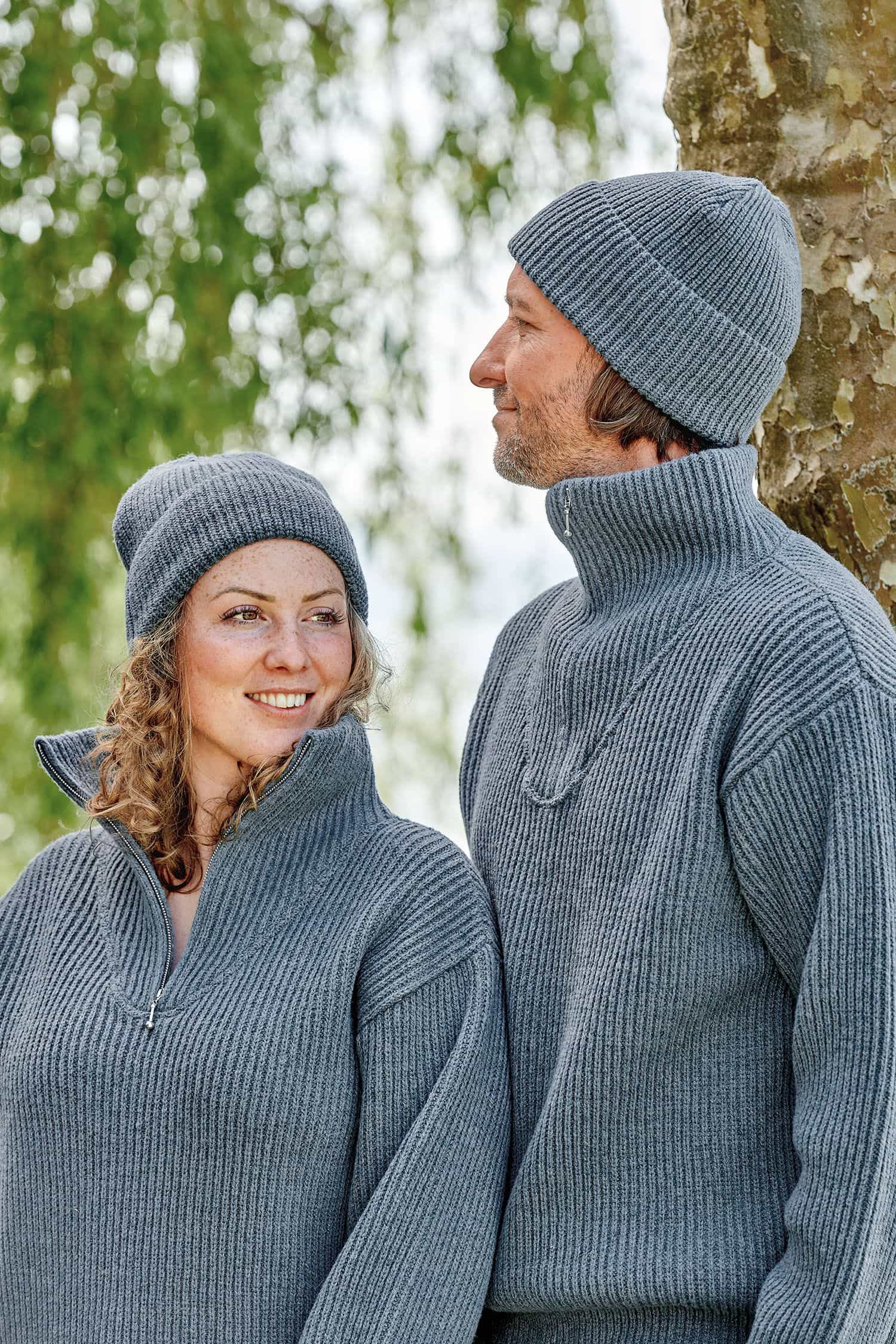Mann und Frau tragen rauchblaue Finkhof Mützen aus bio Wolle (kbT) und passende Troyer