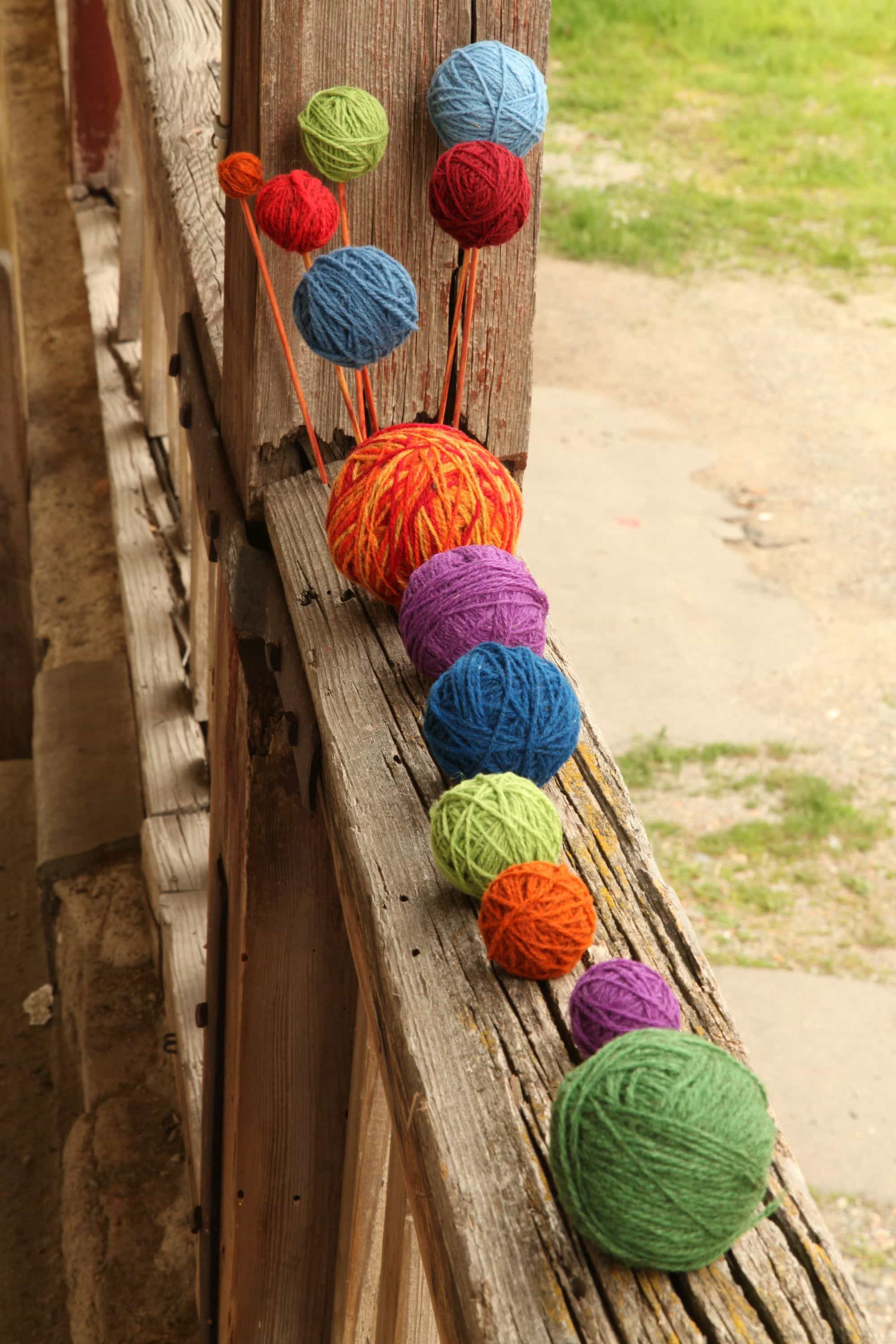 bunte Wollknäule auf Balkongeländer als Banner für Finkhof Strickanleitung einer Wollmütze