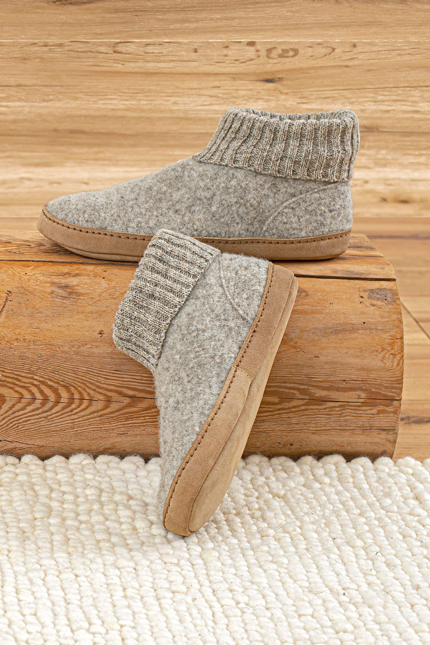 Finkhof-Hüttenschuhe mit Ledersohle hellgraue Finkhof Hüttenschuhe aus pflanzlich gegerbtem Leder und bio Wolle (kbT) auf Holz von der Seite zu sehen