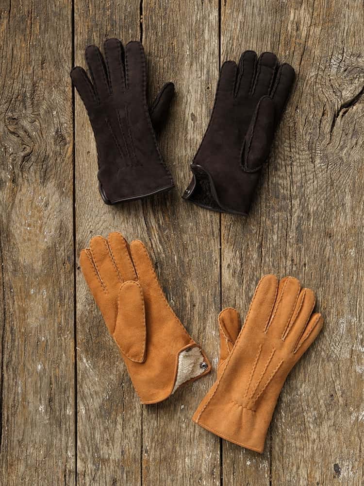 Fell-Fingerhandschuhe Fingerhandschuhe aus Schaffell in verschiedenen Farben auf einem Holzboden