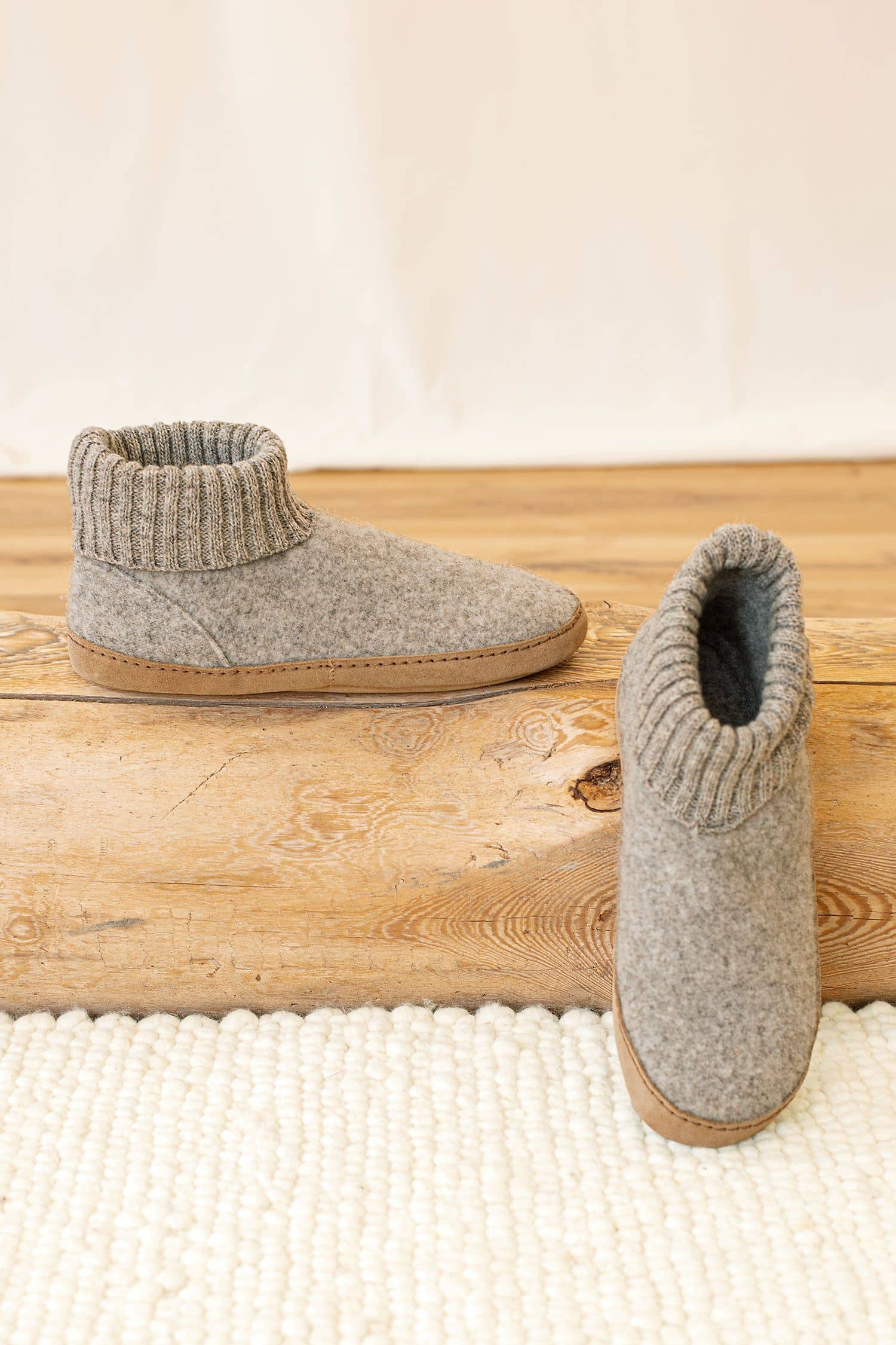 hellgraue Finkhof Hüttenschuhe aus pflanzlich gegerbtem Leder und bio Wolle (kbT) auf Holz