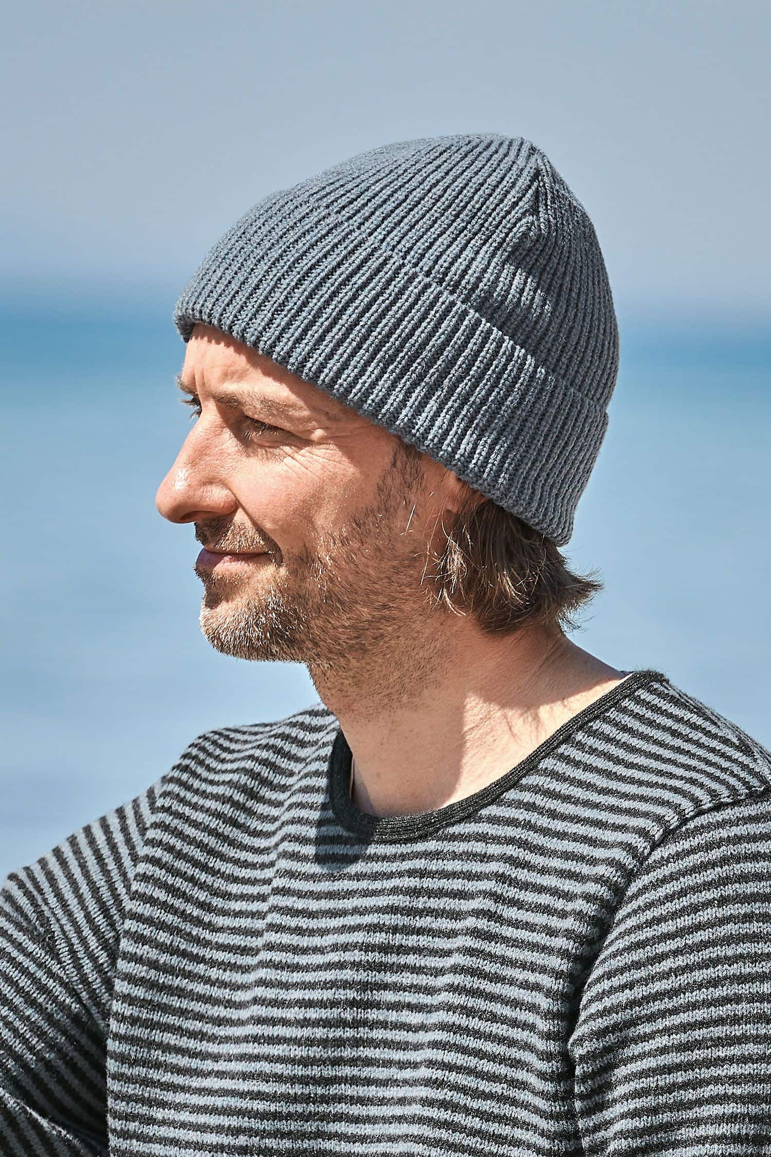 Mann mit Streifenpulli trägt rauchblaue Finkhof Mütze aus bio Wolle (kbT)