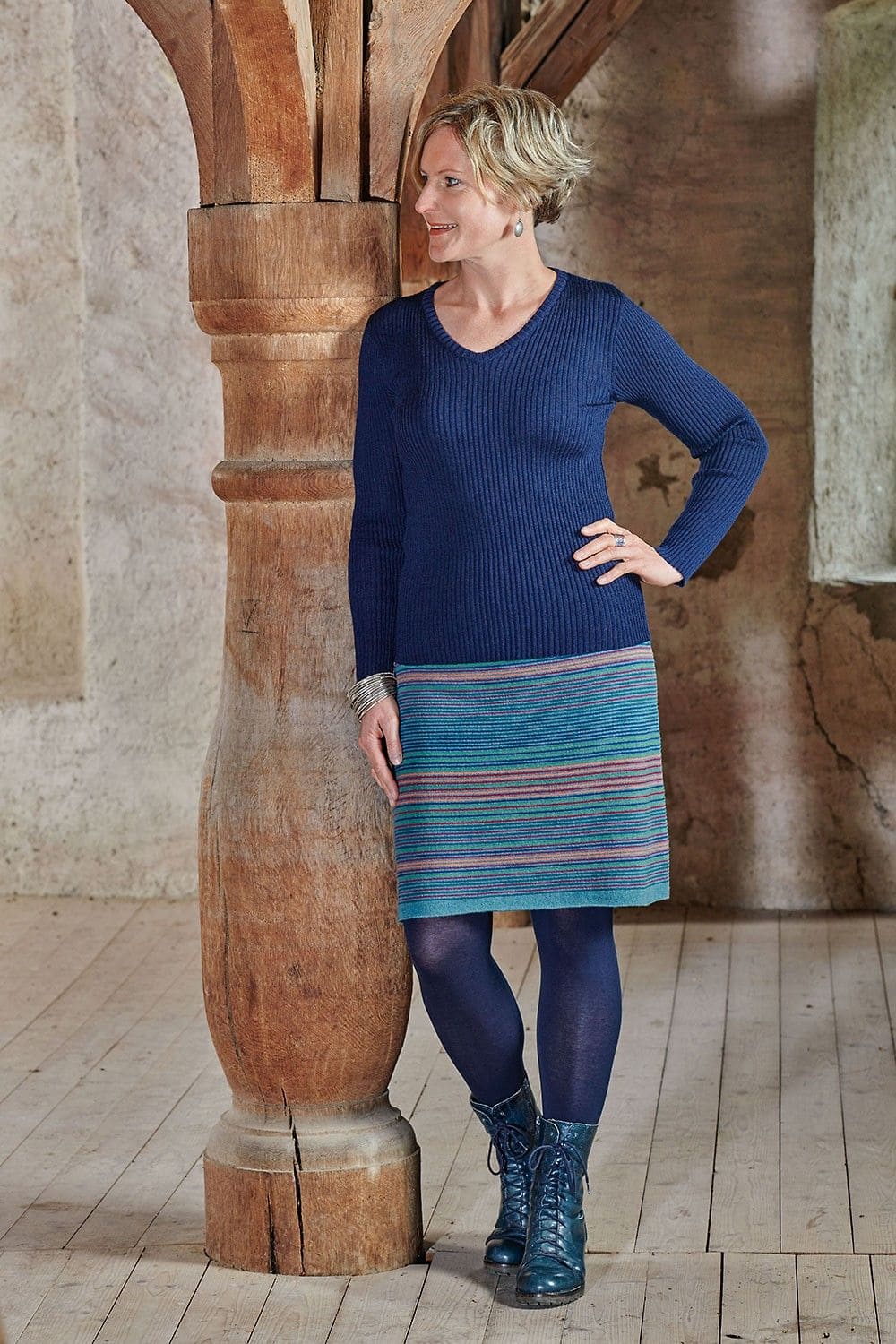 Frau trägt gestreiften Rock, blaue Strumpfhose und blaues Rippshirt mit V Ausschnitt mit bio Wolle (kbT) vom Finkhof