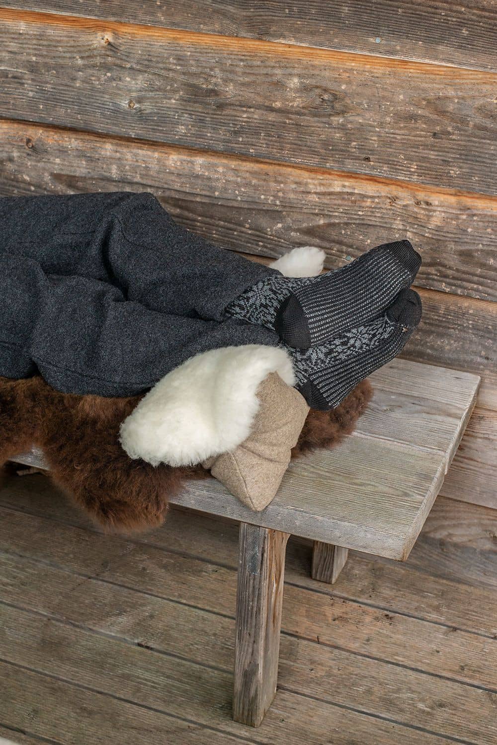 Finkhof Leseknochen aus Schaffell, Loden und Rohwolle (kbT), liegt auf Bank und jemand legt seine Füße darauf
