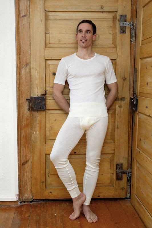 naturweiße lange Wolle Seide Unterhose für Herren aus bio Wolle (kbT) und Seide getragen mit kurzem Shirt vor Holztür