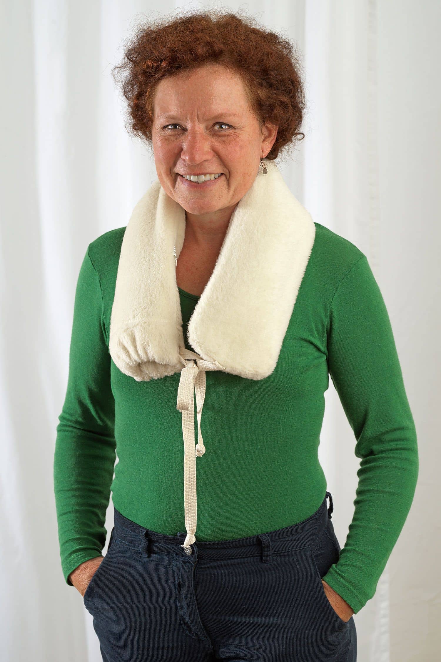 Frau hat sich lange Wärmflasche mit Lammflorbezug aus Wolle und bio Baumwolle (kbA) vom Finkhof über Schultern gelegt