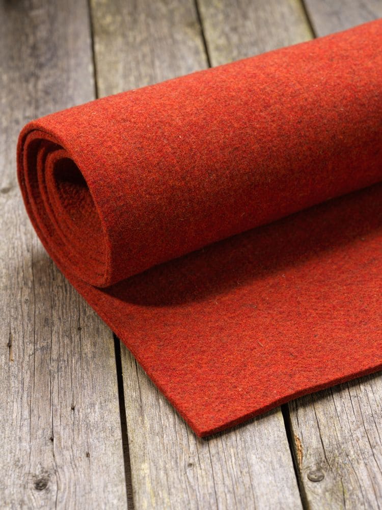oranger/ sienafarbener Nadelfilz als Rolle auf braunem Holzboden