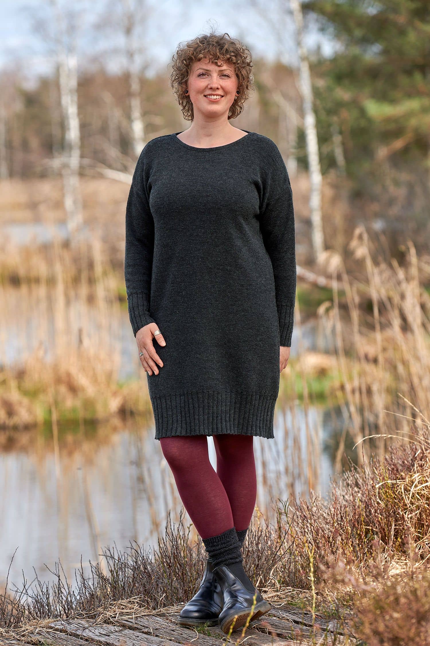 Frau mit roter Strumphose trägt ein anthrazitgraues Strickkleid aus bio Wolle (kbT)