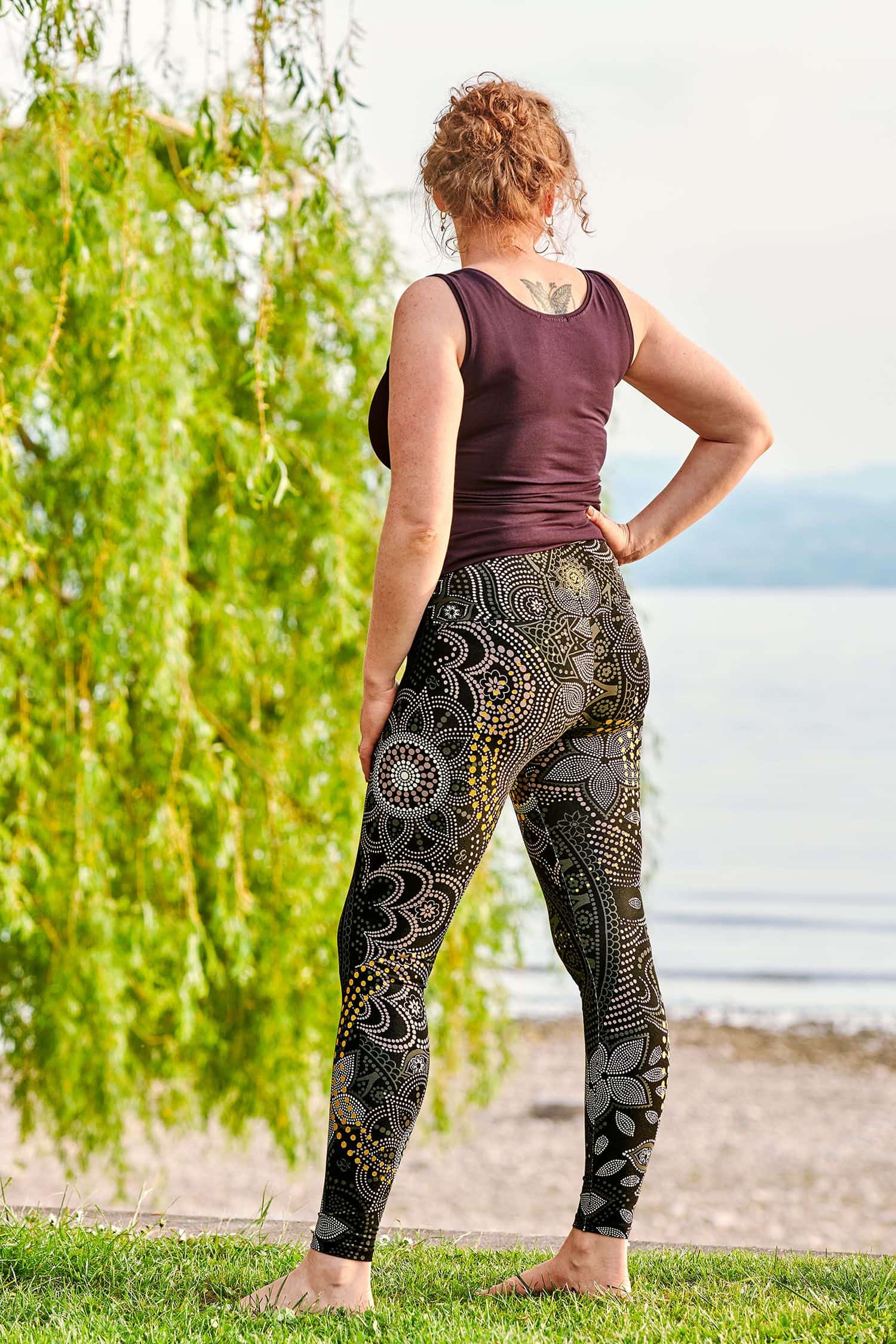 Rückansicht von Frau mit  grau gemusterter metallic Yoga Leggings aus bio Baumwolle (kbA) und Elasthan und lila Top