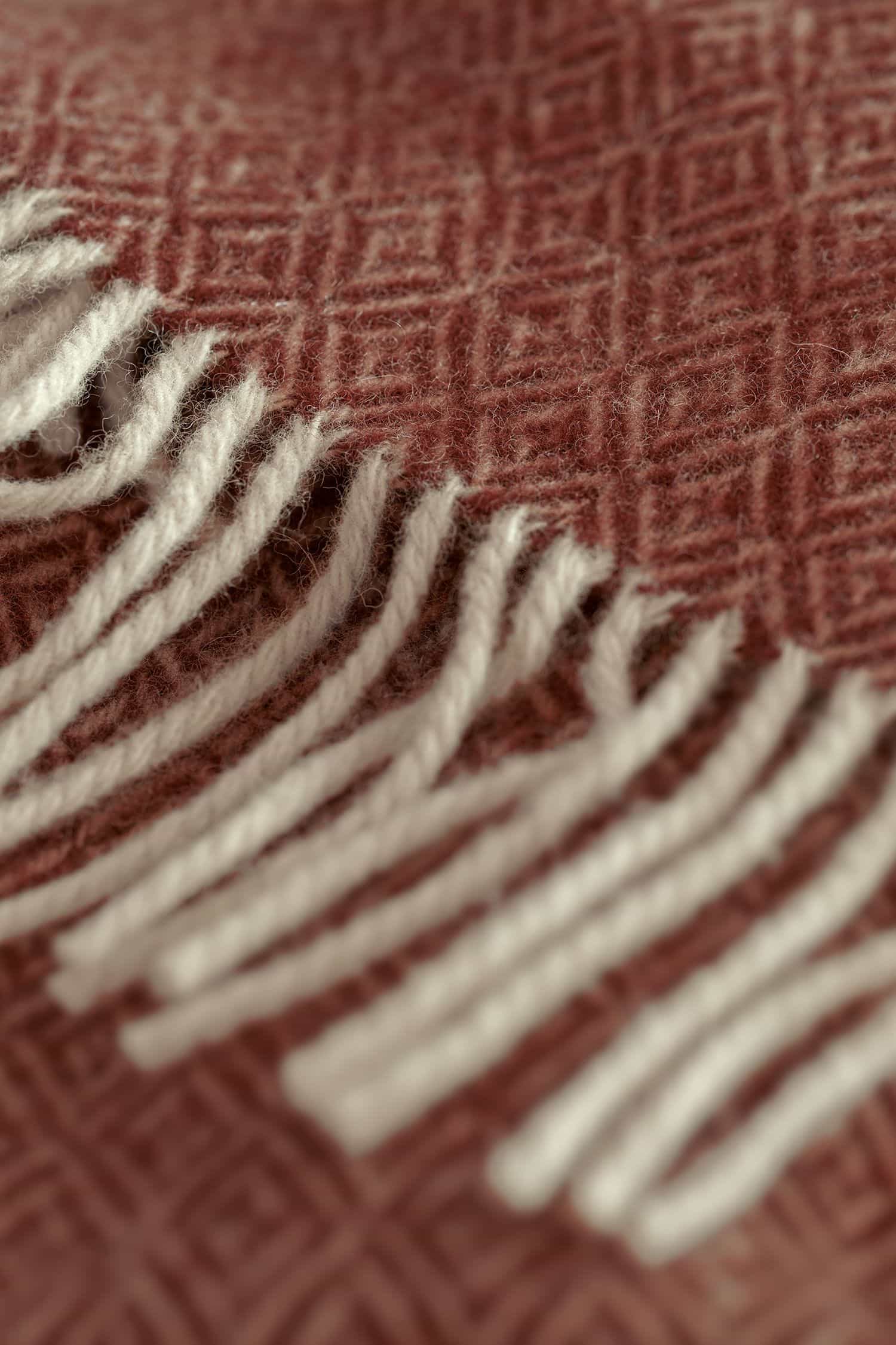 Detailaufnahme der naturweißen Fransen des altrosafarbenen Finkhof Plaid Siena aus bio Wollle (kbT)