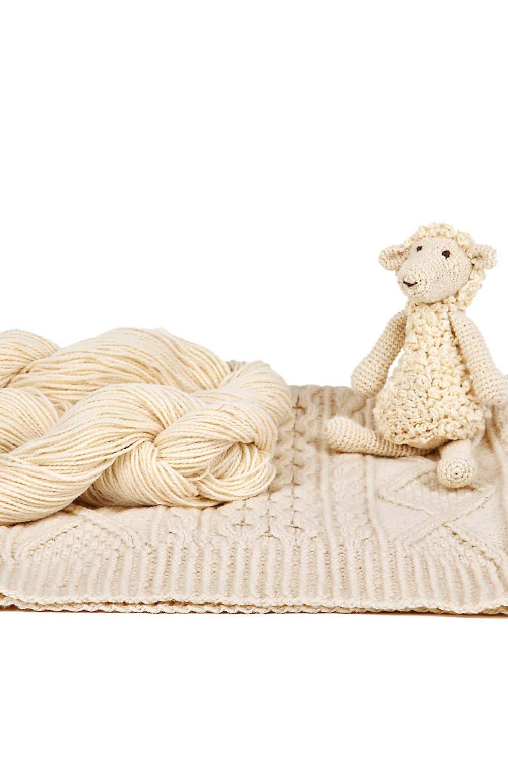 Weiße Merino-Strickwolle dünn vom Finkhof dünne Finkhof Merinowolle aus bio Wolle (kbT) in naturweiß auf Strickdecke mit Strickschaf