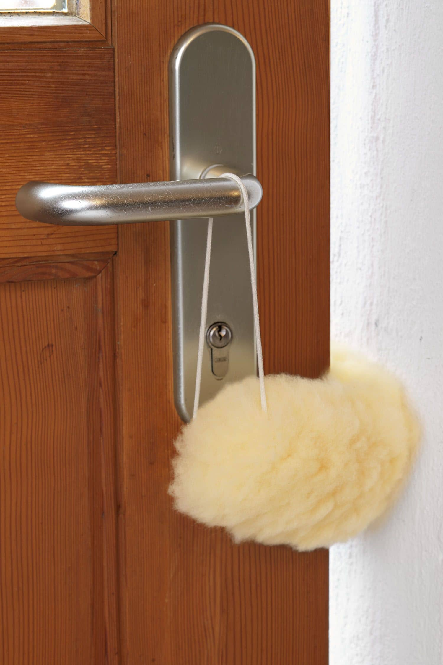 gelblicher Türstopper für die Türklinke aus relugan gegerbtem Schaffell vom Finkhof, hängt an einer Türklinke