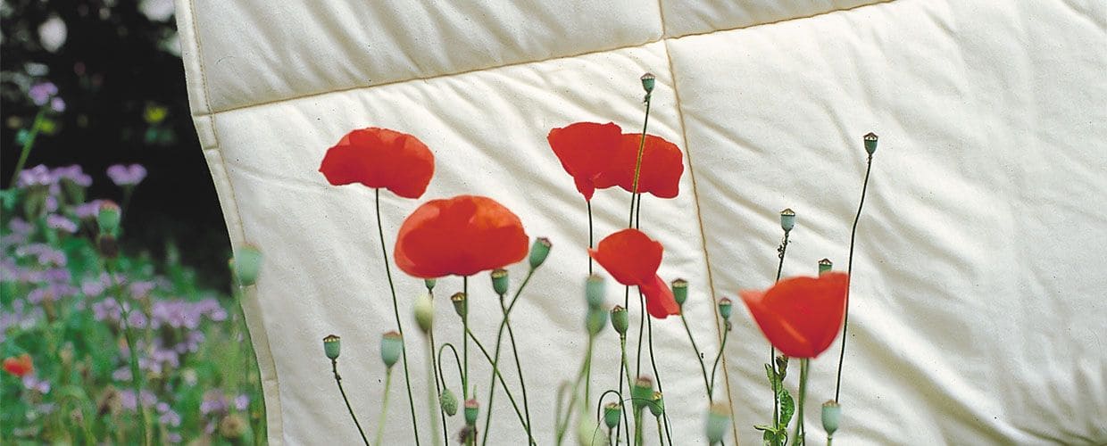 Ecke einer Bettdecke hinter Blumen