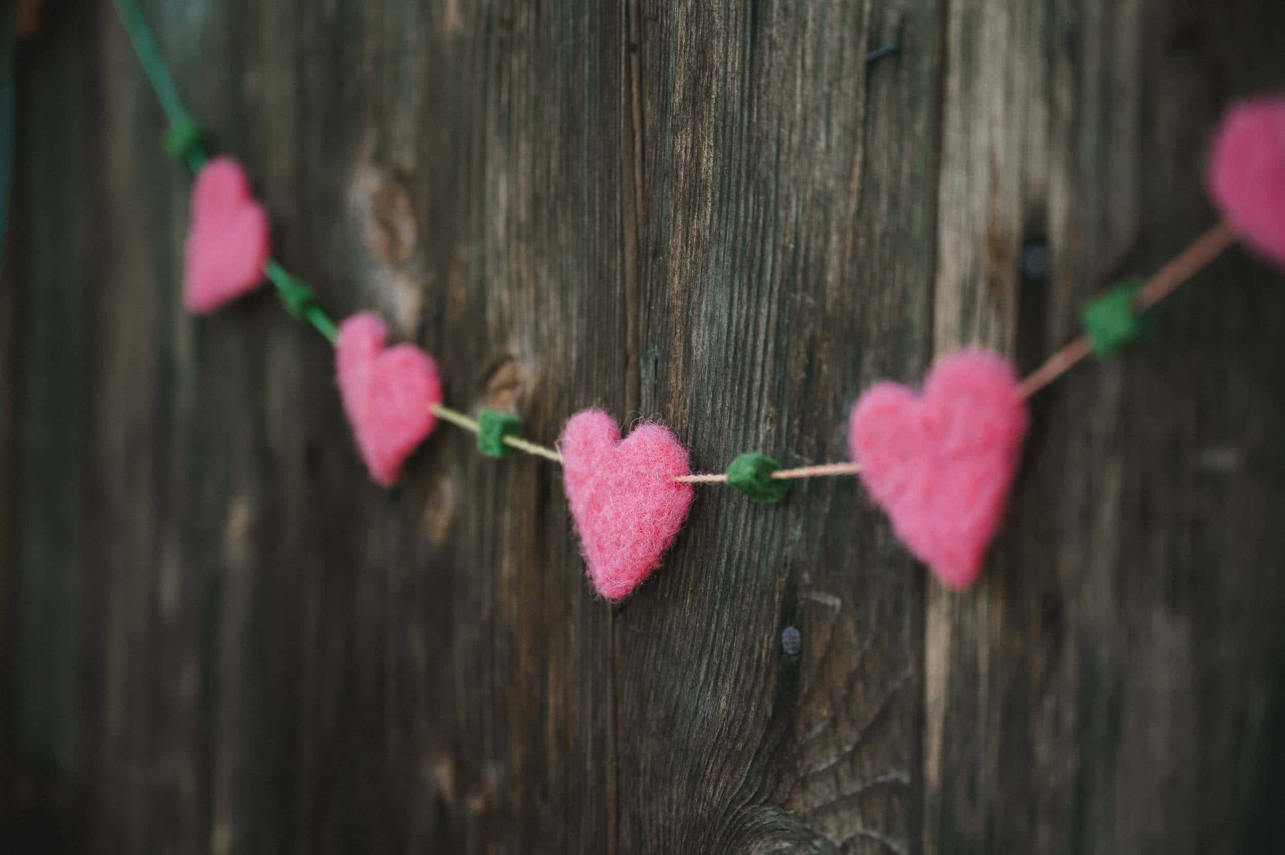 pinke Girlande aus Filzherzen zu Muttertag an einer Holzwand
