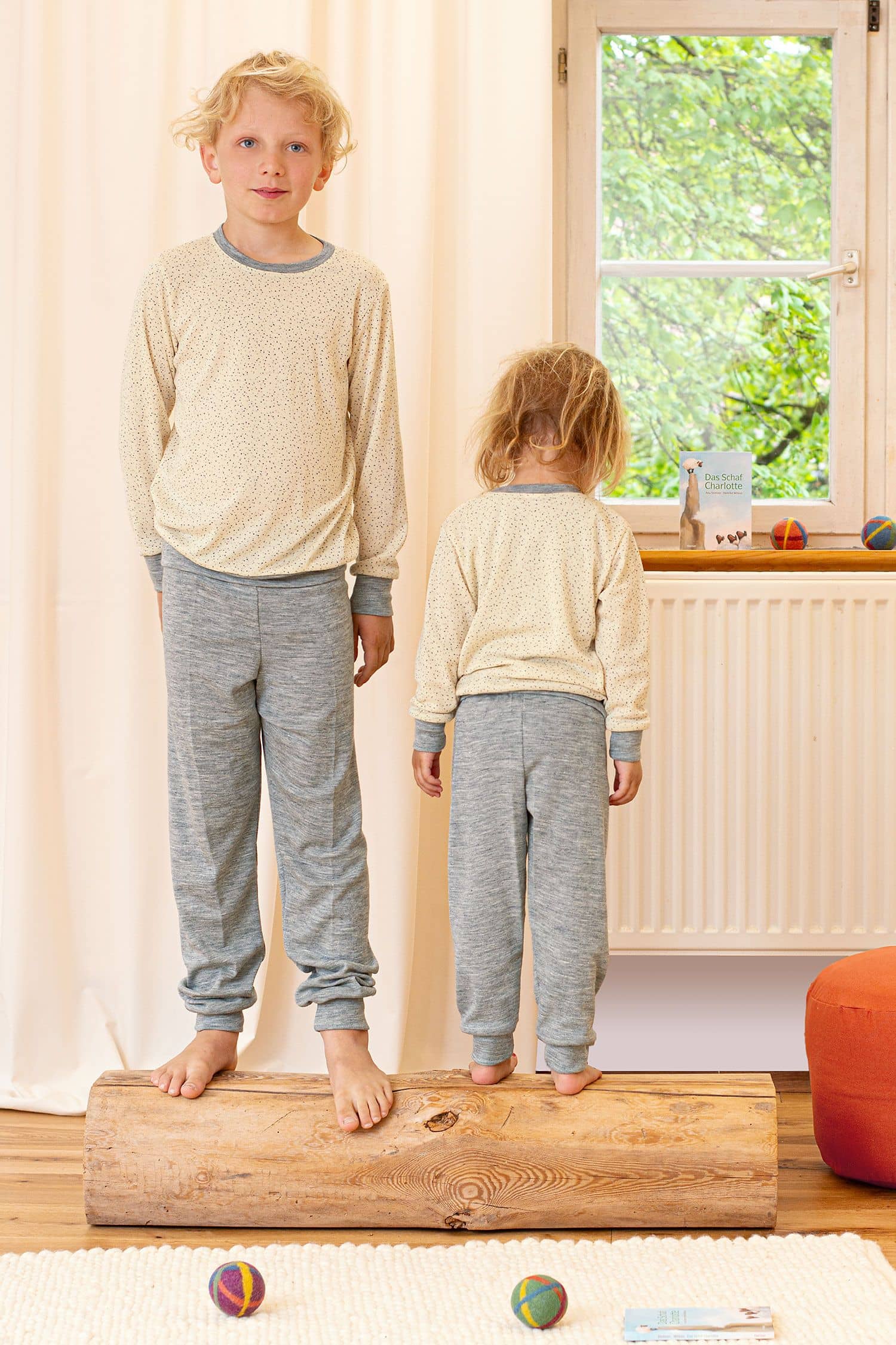 Kinder stehen auf Balken und tragen Schlafanzughose und Oberteil mit Punkten aus bio Wolle (kbT) und Seide