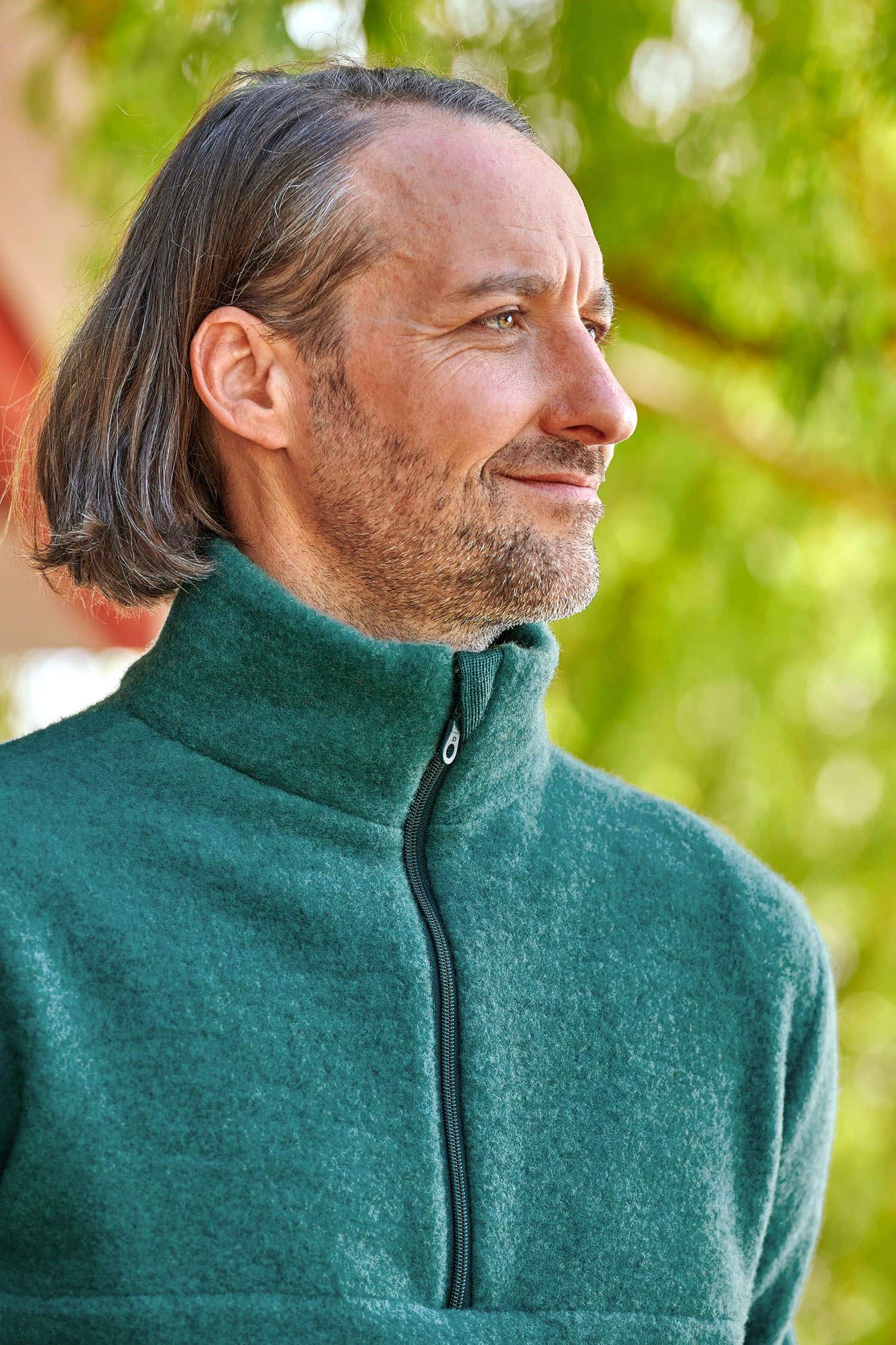 Portraitaufnahme von Mann mit türkisem Pulli mit hohem Kragen und Reißverschluss aus bio Wolle (kbT) vom Finkhof