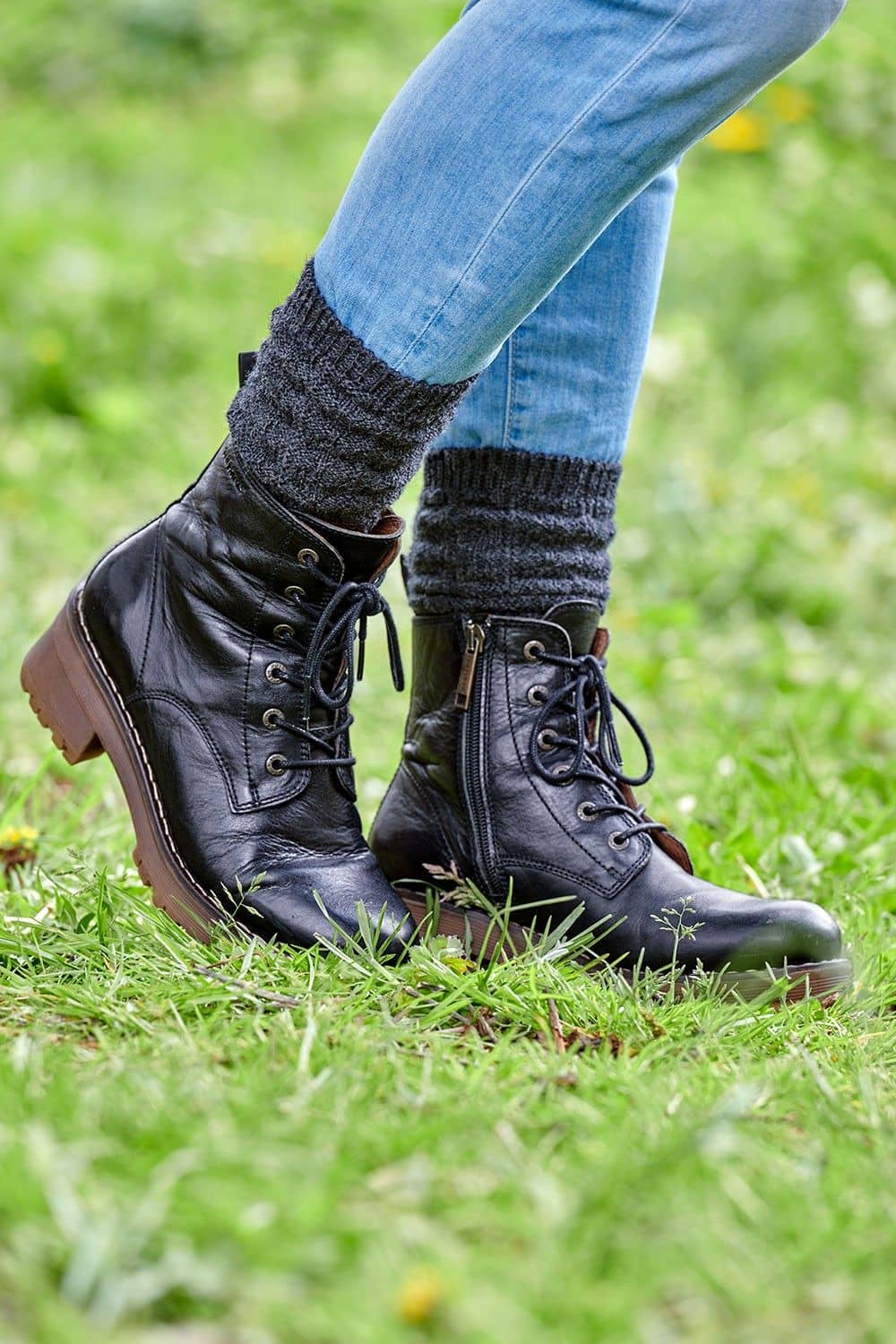 Person steht auf Wiese und trägt dunkelgraue Struktursocken aus bio Wolle (kbT) vom Finkhof mit Stiefeln und Jeans