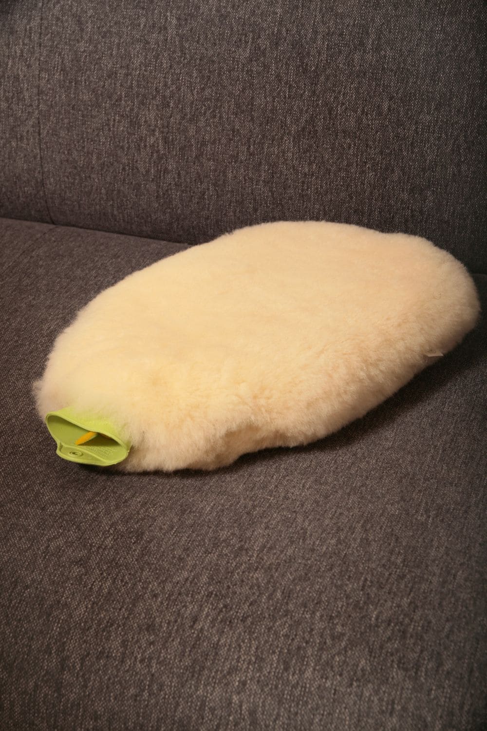 Wärmehülle groß große relugan gegerbte Wärmehülle für Wärmflasche vom Finkhof mit grüner Wärmflasche auf grauem Sofa