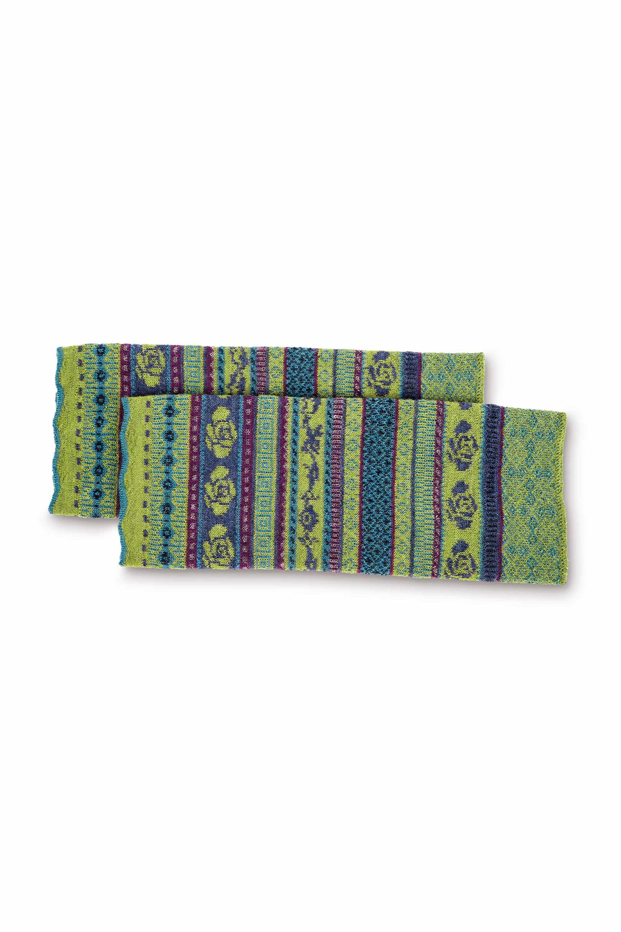 Frau vor Baum trägt grünes Shirt, blauen Cardigan, gemusterten Cacheur und Beinstulpen in farn aus bio Wolle (kbT)