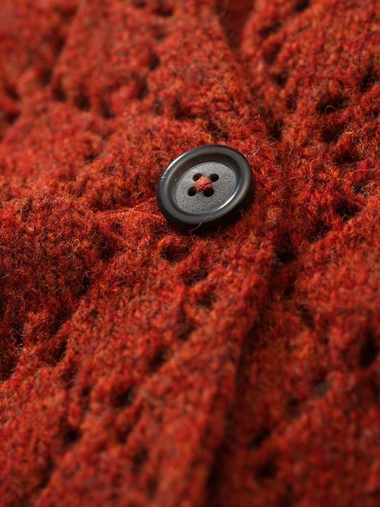 Nahaufnahme der Struktur und einem Knopf der sienafarbenen Strickjacke mit Ajourmuster aus Bio-Wolle vom Finkhof