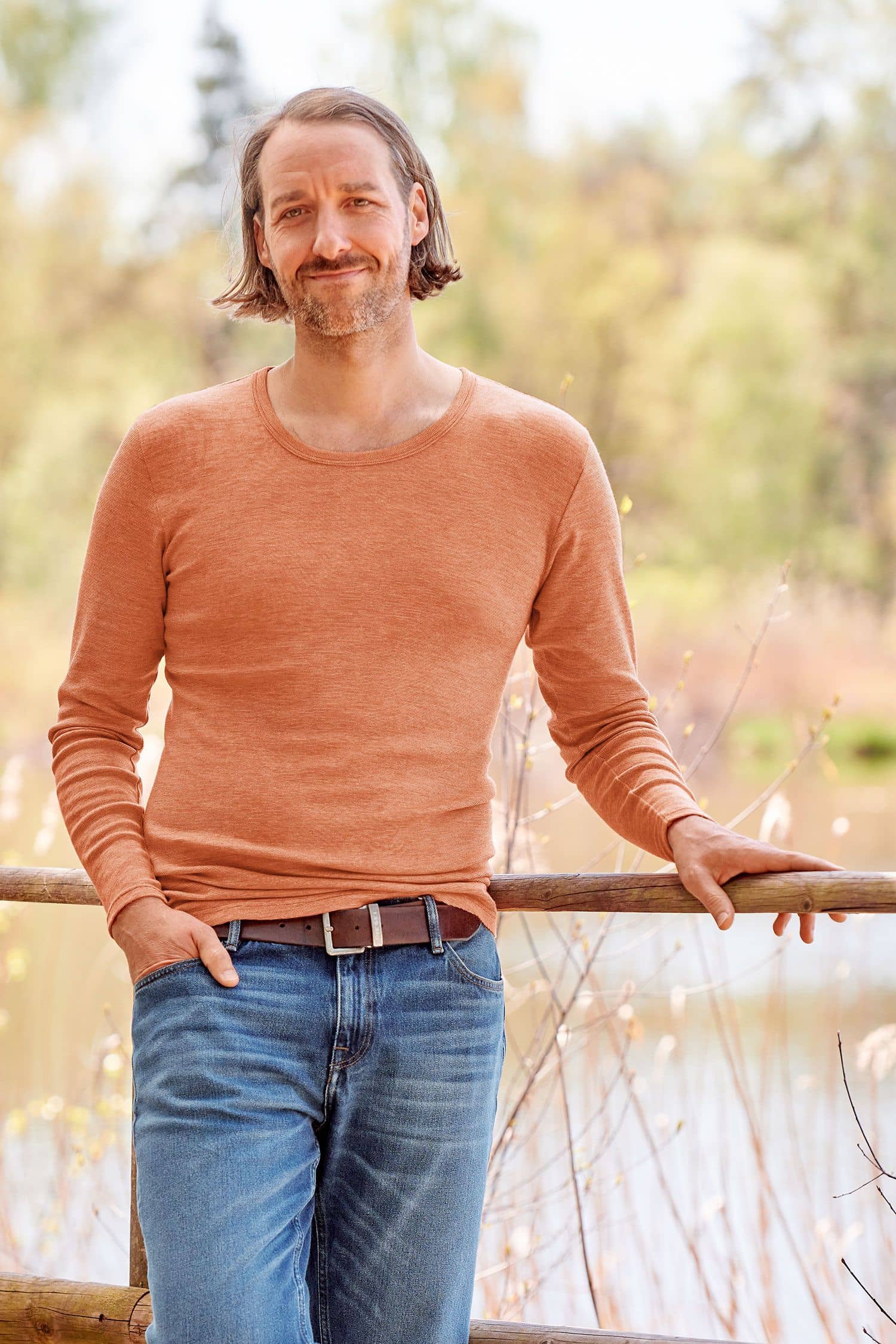 Mann mit Jeans trägt oranges Langarmshirt aus bio Wolle (kbT), bio Baumwolle (kbA) und Seide