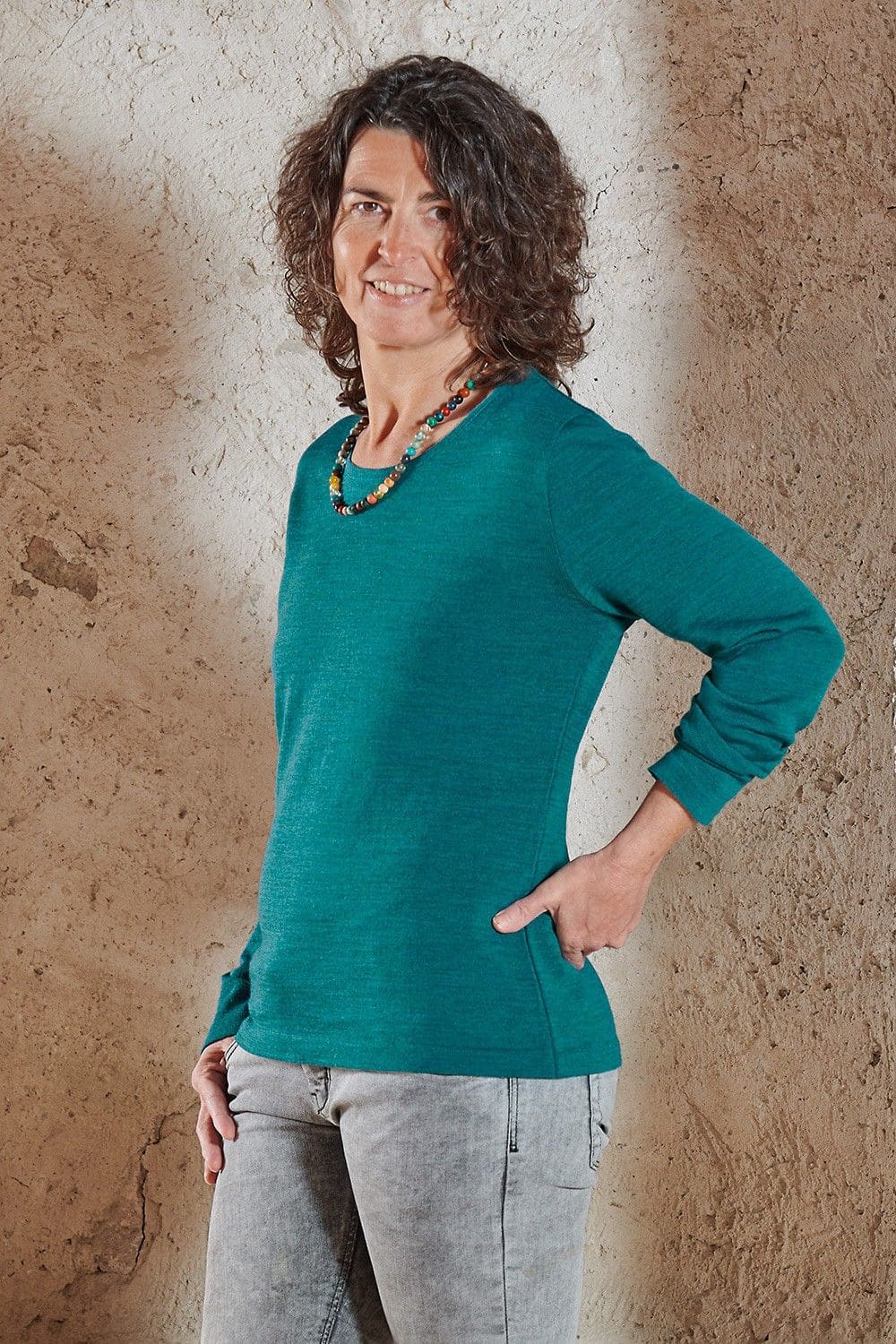 Frau mit bunter Perlenkette und petrolblauem Wollshirt aus bio Wolle (kbT) vom Finkhof
