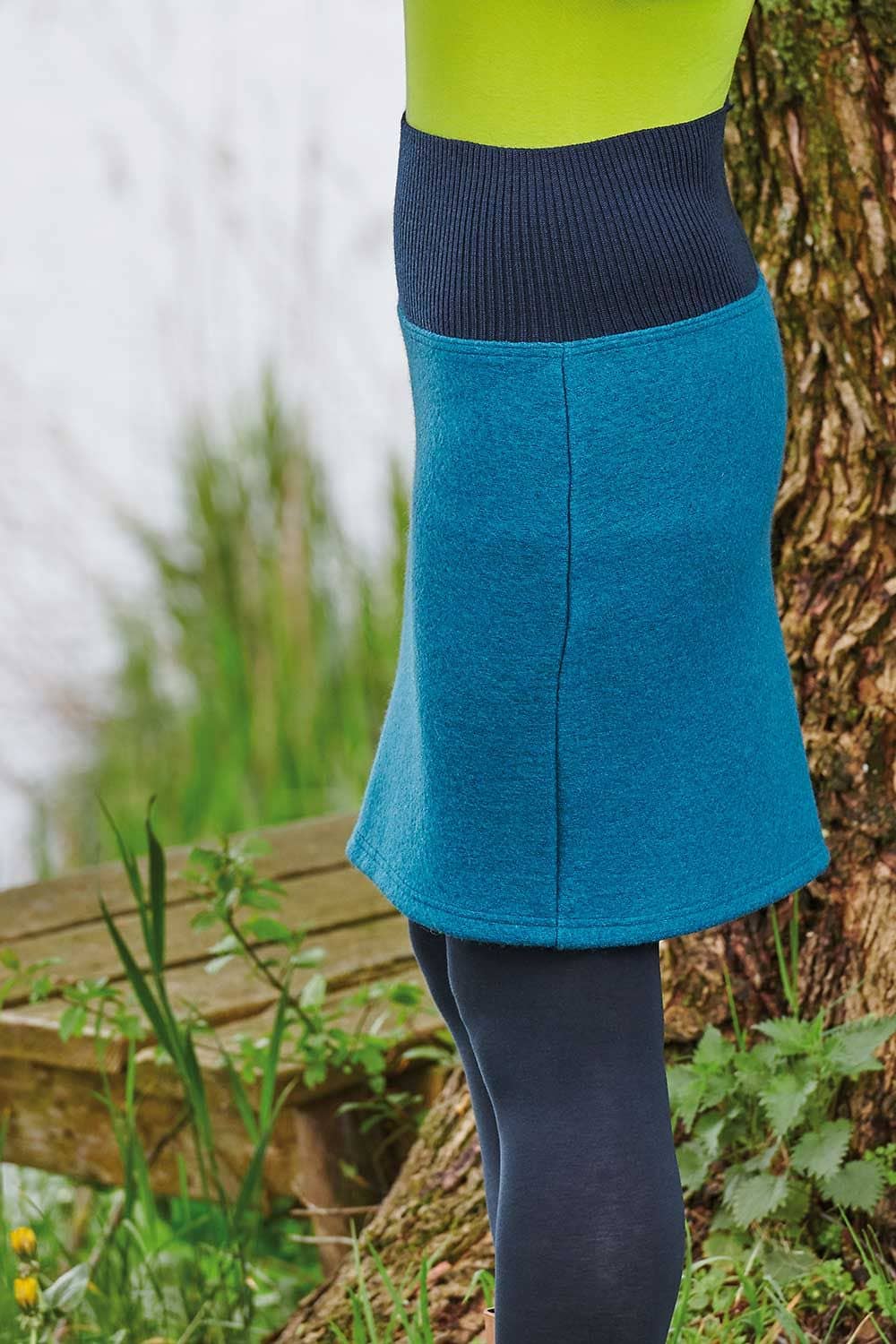 Nahaufnahme von türkisem unifarbenen Walkrock aus bio Wolle (kbT) von der Seite mit grünem Shirt