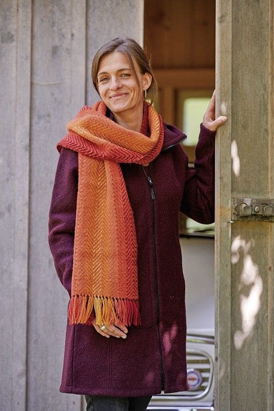 Pflanzengefärbter Wollschal -handgewebt- herbstlaub Frau mit Mantel trägt pflanzengefärbten und handgewebten Wollschal aus bio Wolle (kbT) vom Finkhof in orangetönen